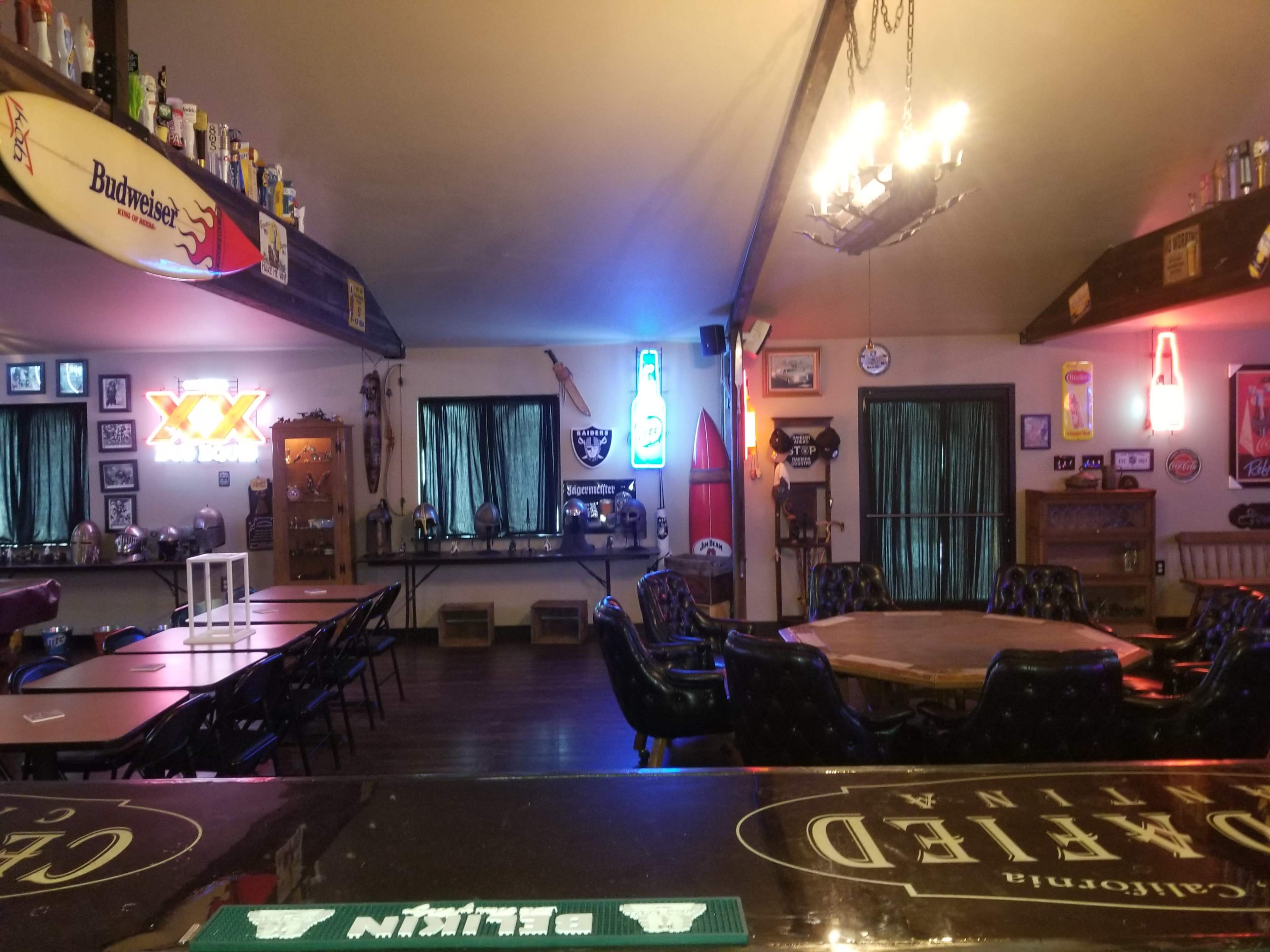 An interior of a bar with various neon lights, tables, and chairs arranged in a cozy layout.