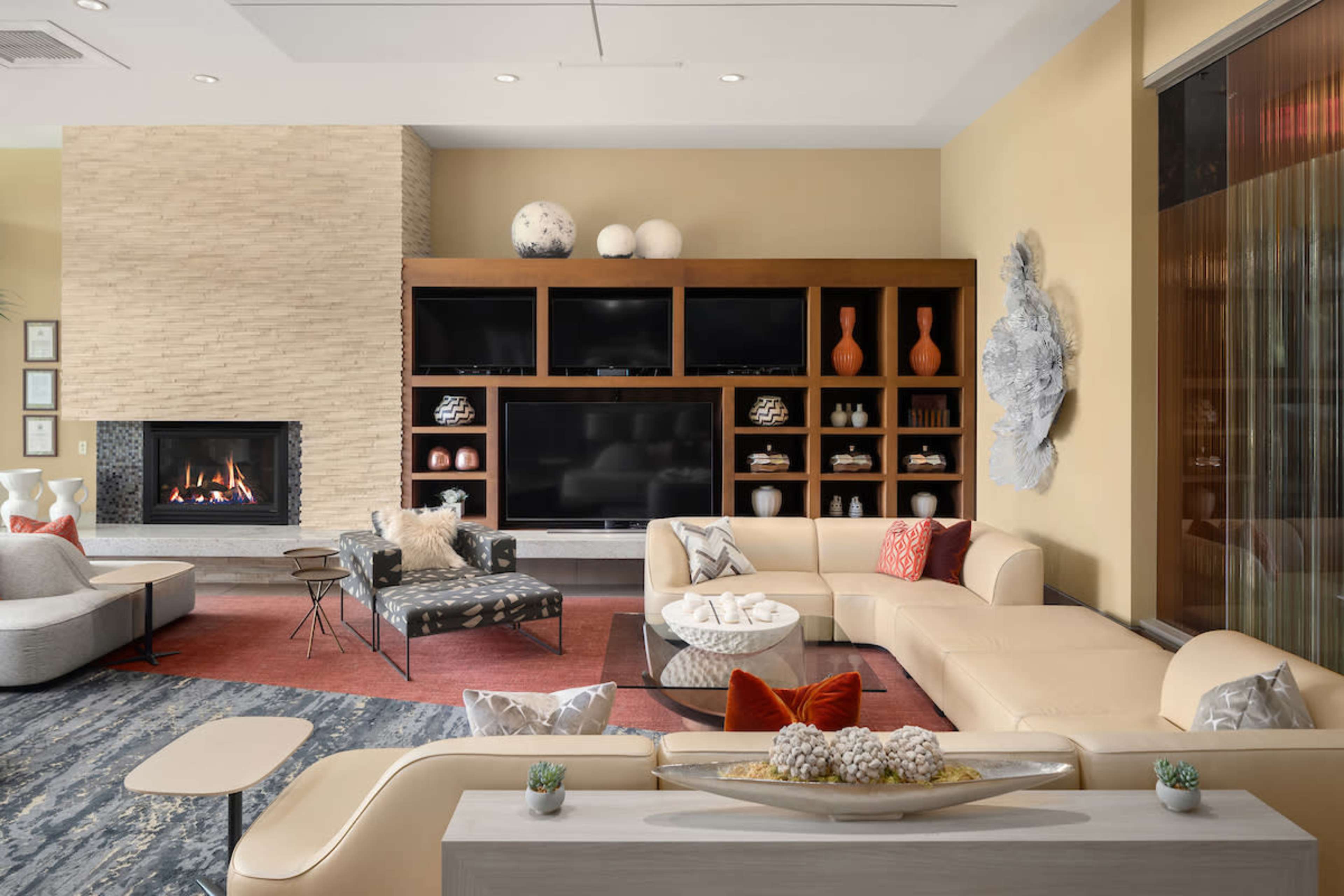 A modern living room features a fireplace, a large television unit, and contemporary furniture arranged around a central coffee table.