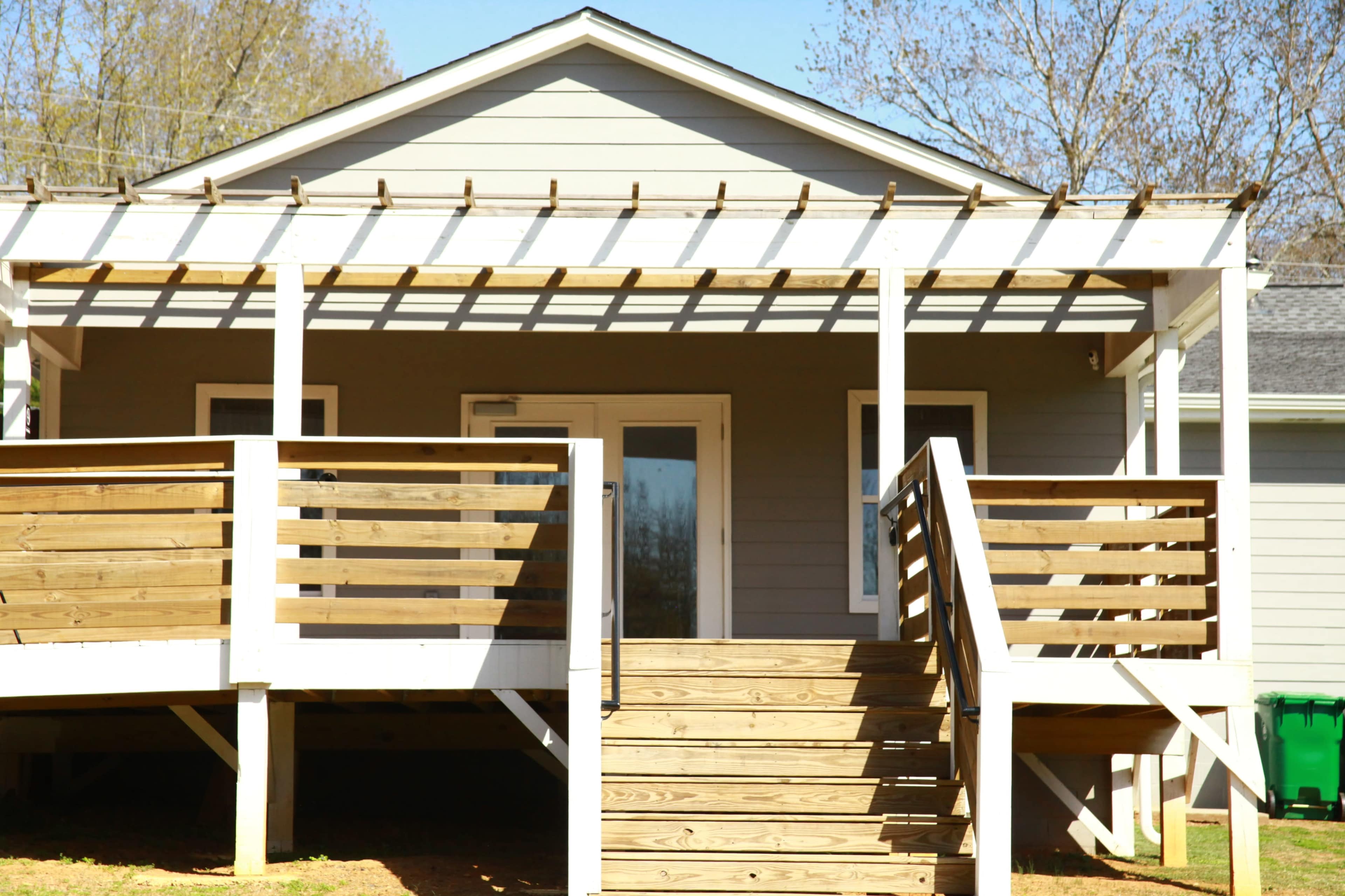 A single-story house with a covered porch and wooden steps leading to the entrance.