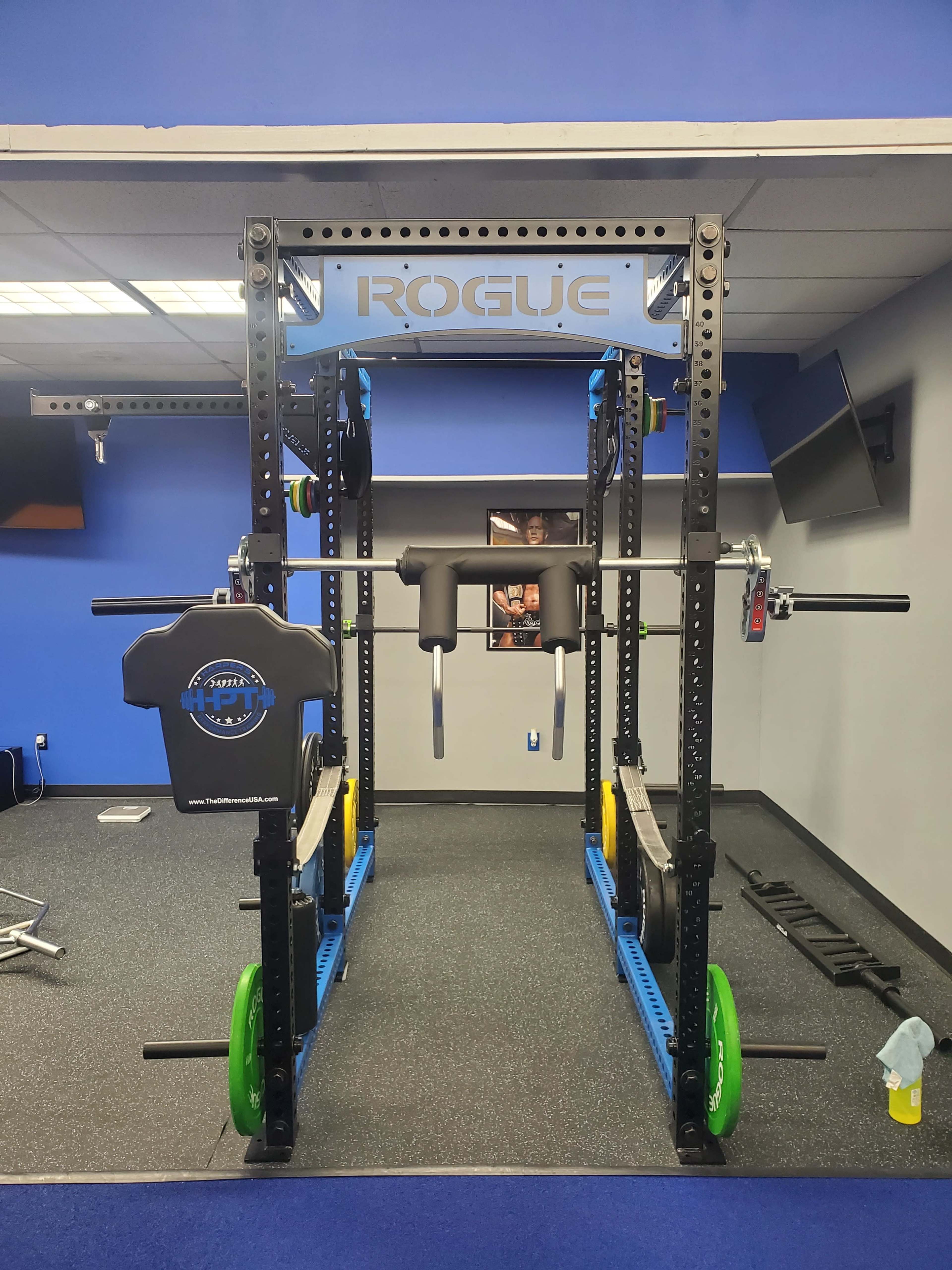 A black and blue weightlifting rack with a barbell and weight plates in a gym setting.