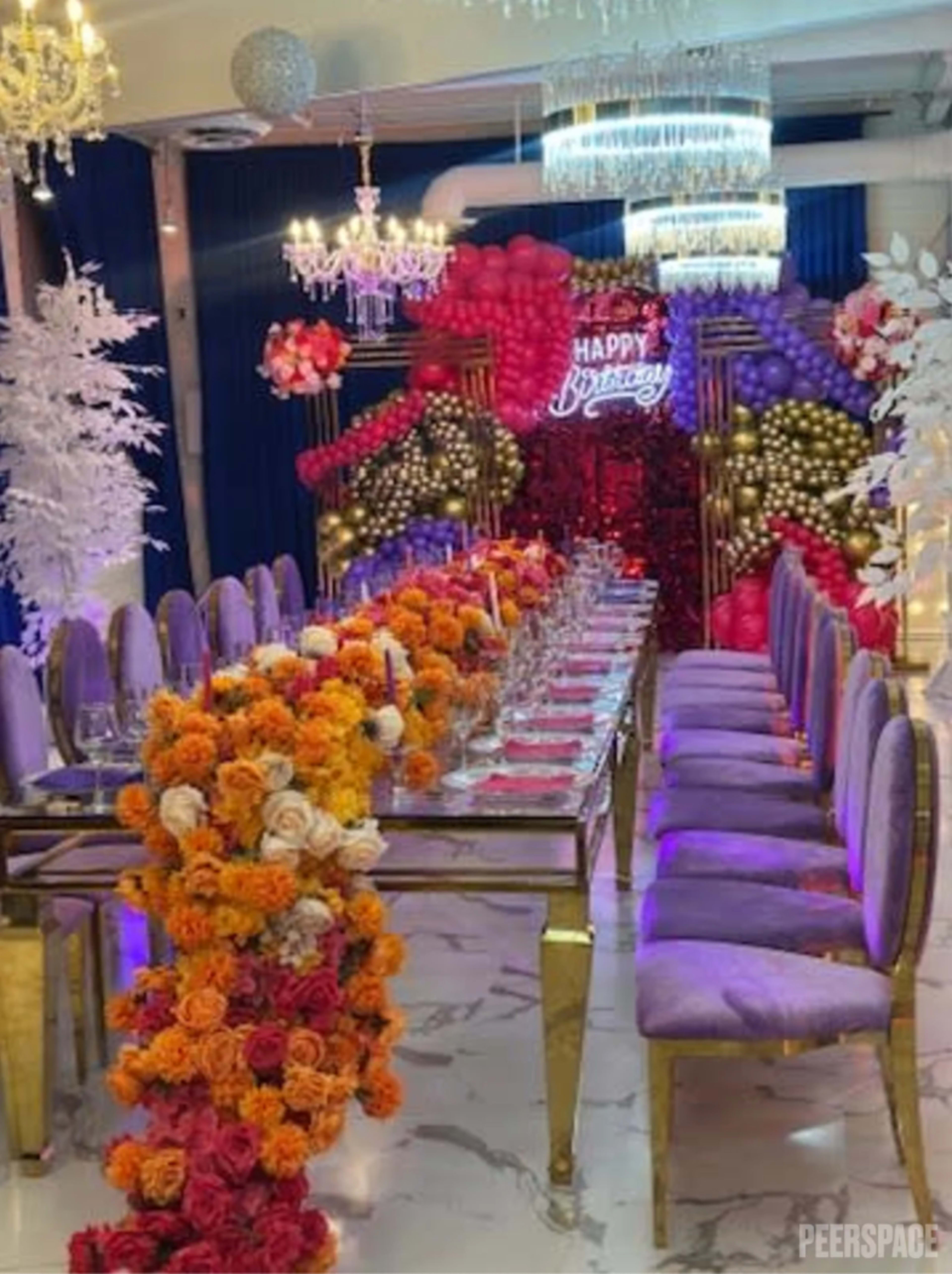 The image shows a decorated birthday celebration setup with a long table adorned with flowers and colorful balloons in the background.
