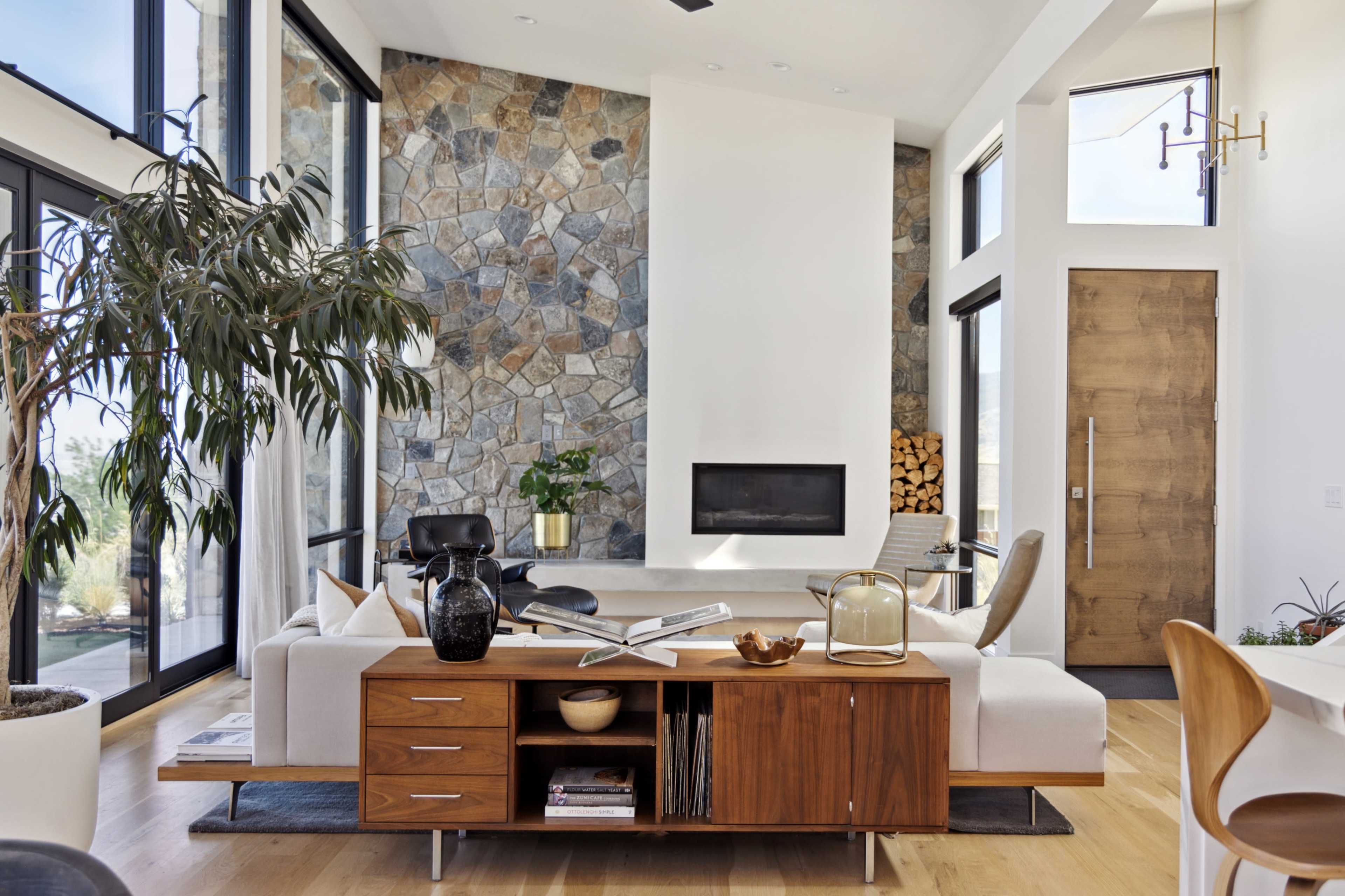 The image shows a modern living room featuring a stone accent wall, a sleek sofa, and a wooden coffee table with decorative items.