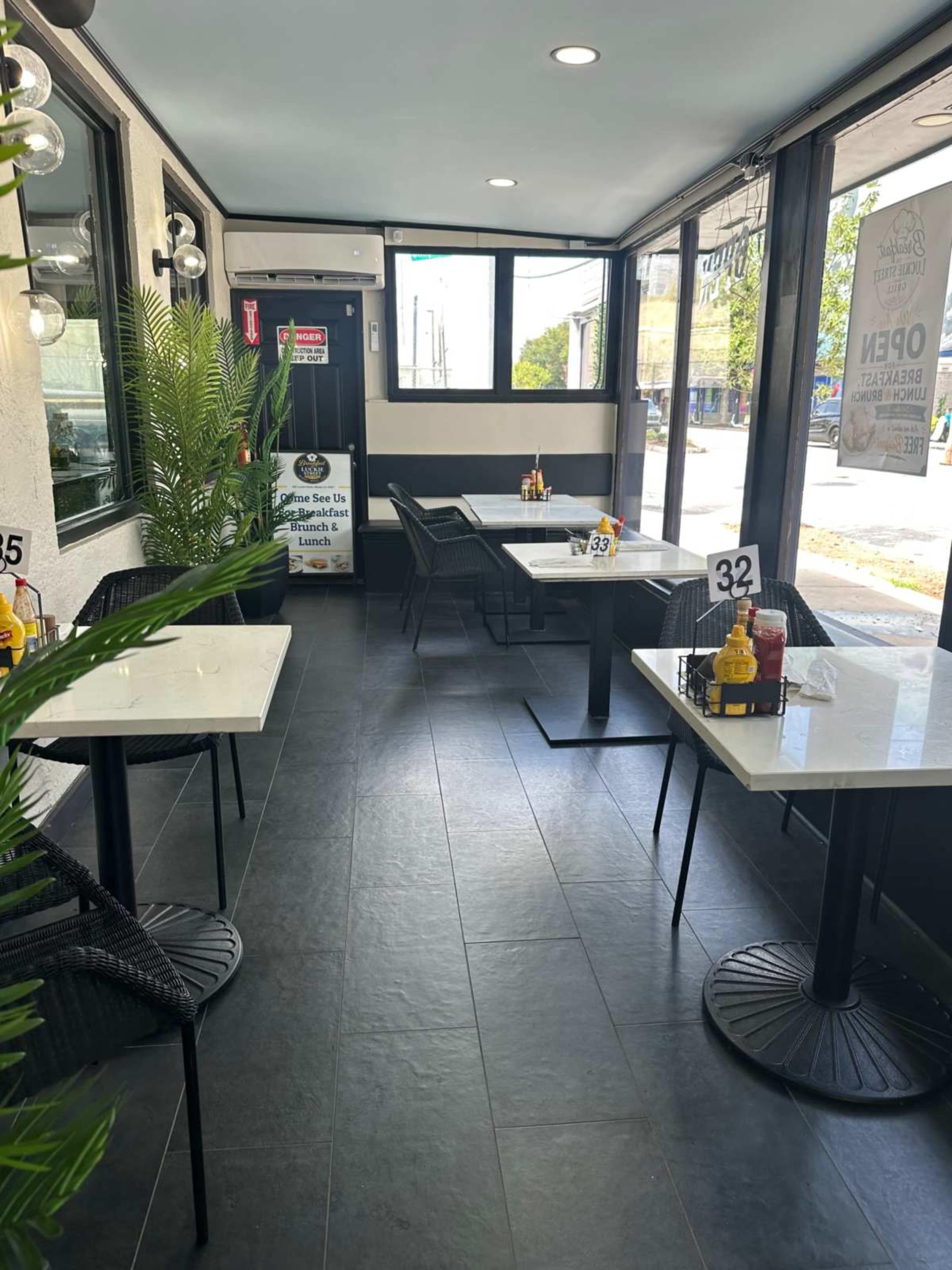 The image shows the interior of a casual dining restaurant with tables set for customers and a large window letting in natural light.