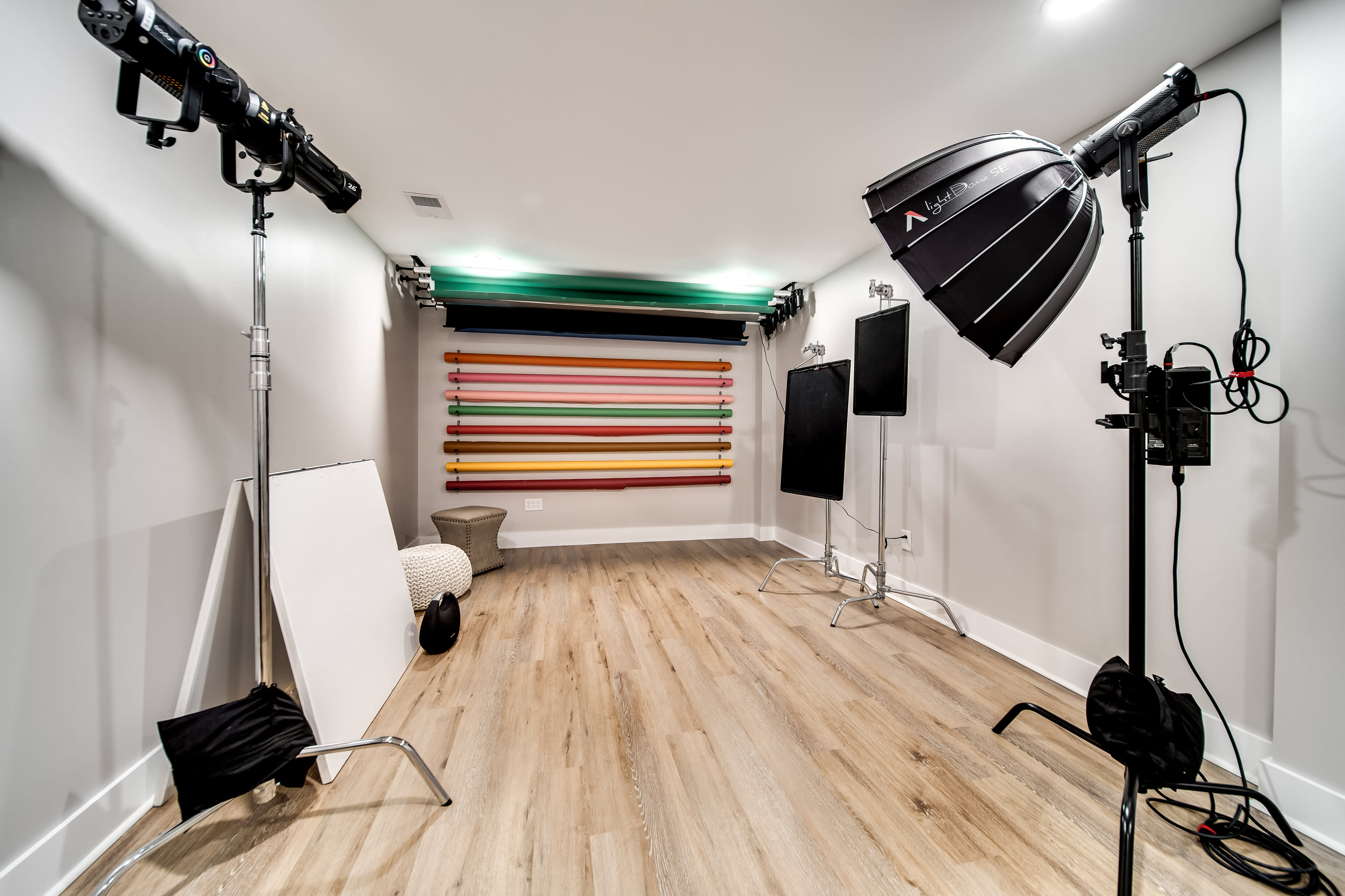 The image shows a photography studio with backdrops, lighting equipment, and props arranged on a wooden floor.