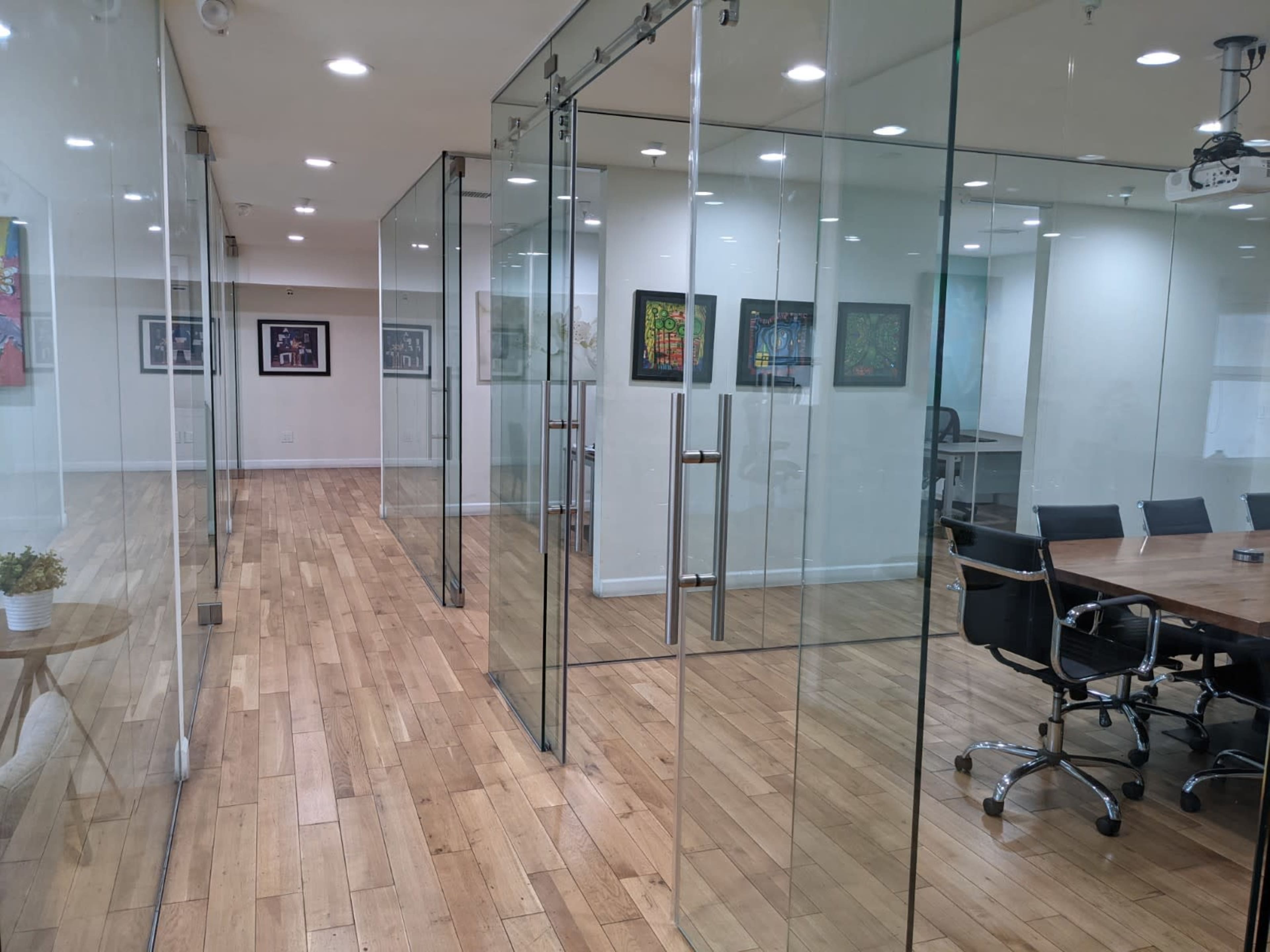 A modern office space with glass-walled meeting rooms and a large wooden conference table.