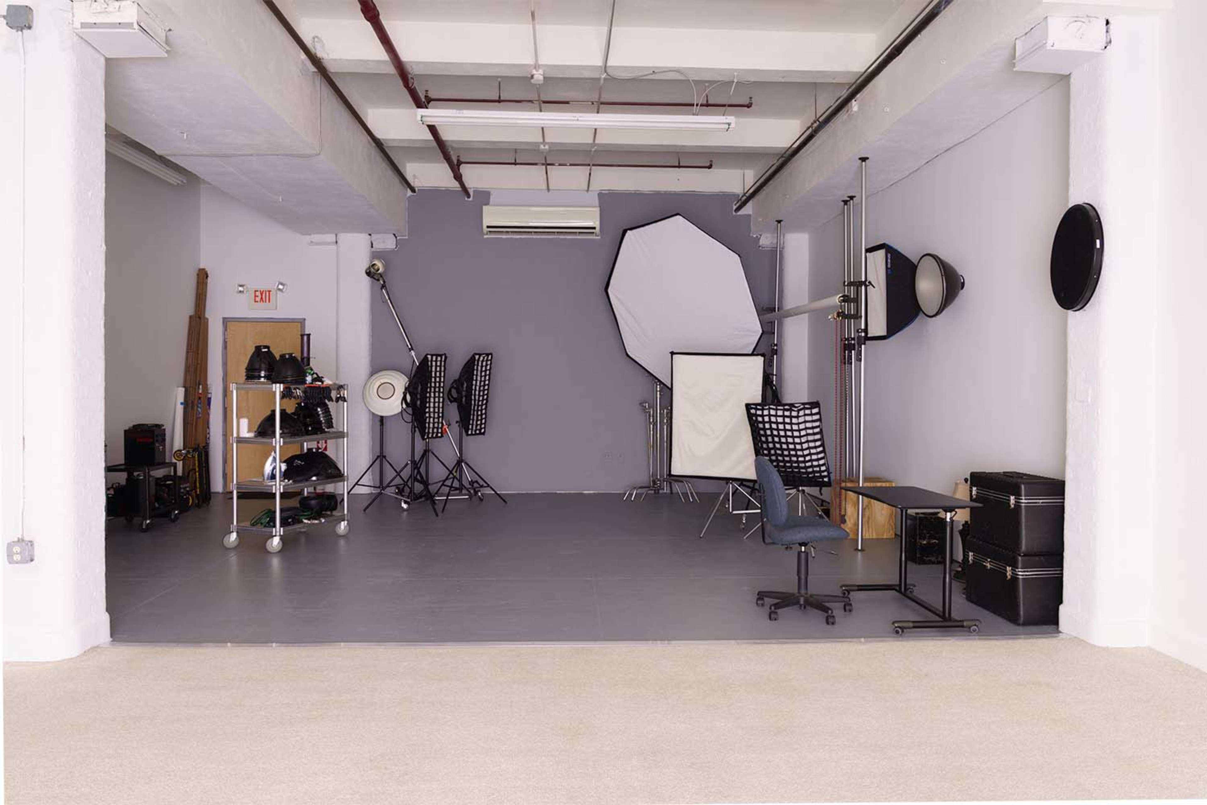 A spacious photography studio with various lighting equipment, backdrops, and storage cases.