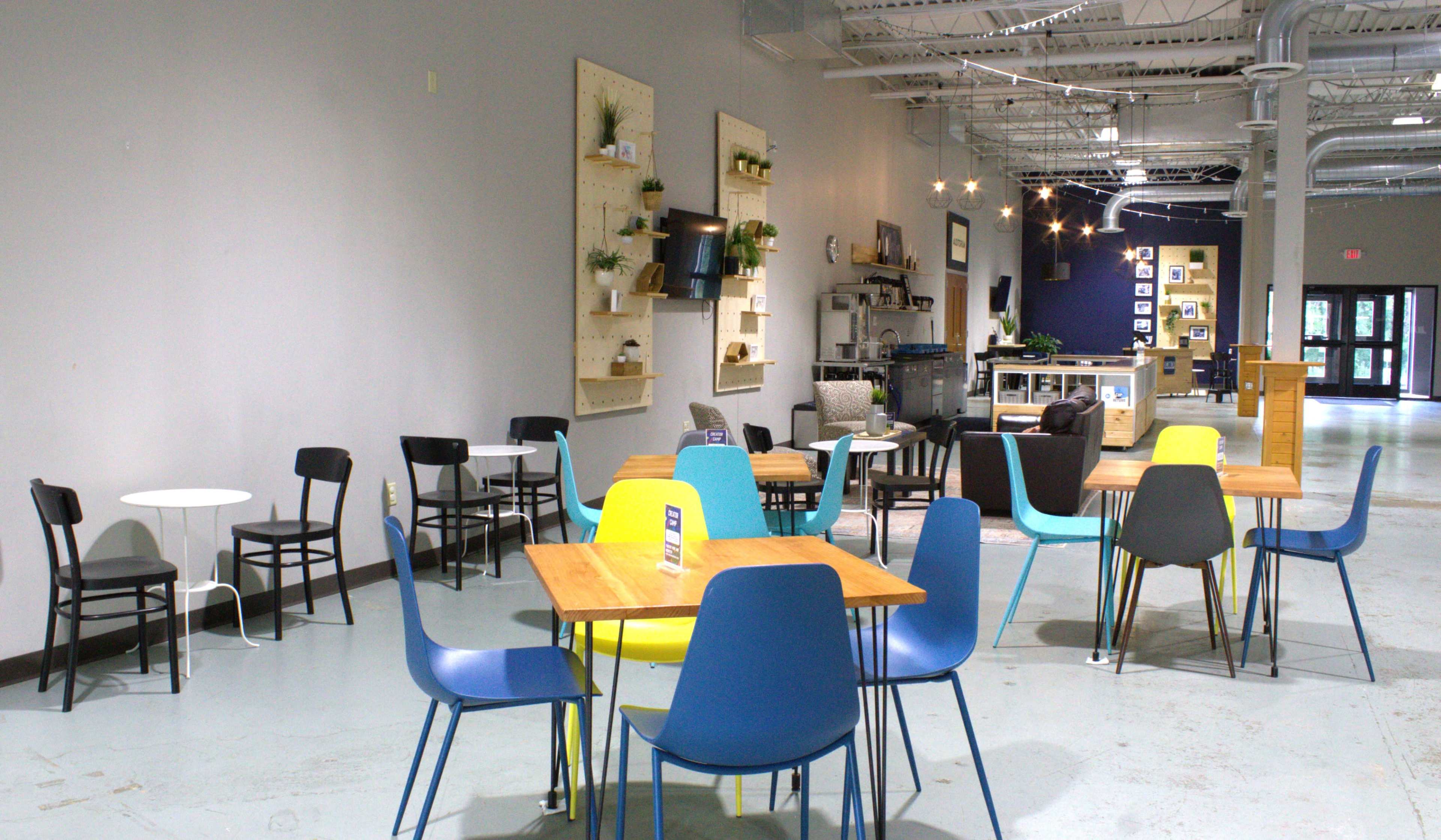 The image shows a spacious cafe interior with various tables and chairs arranged casually on a polished concrete floor.