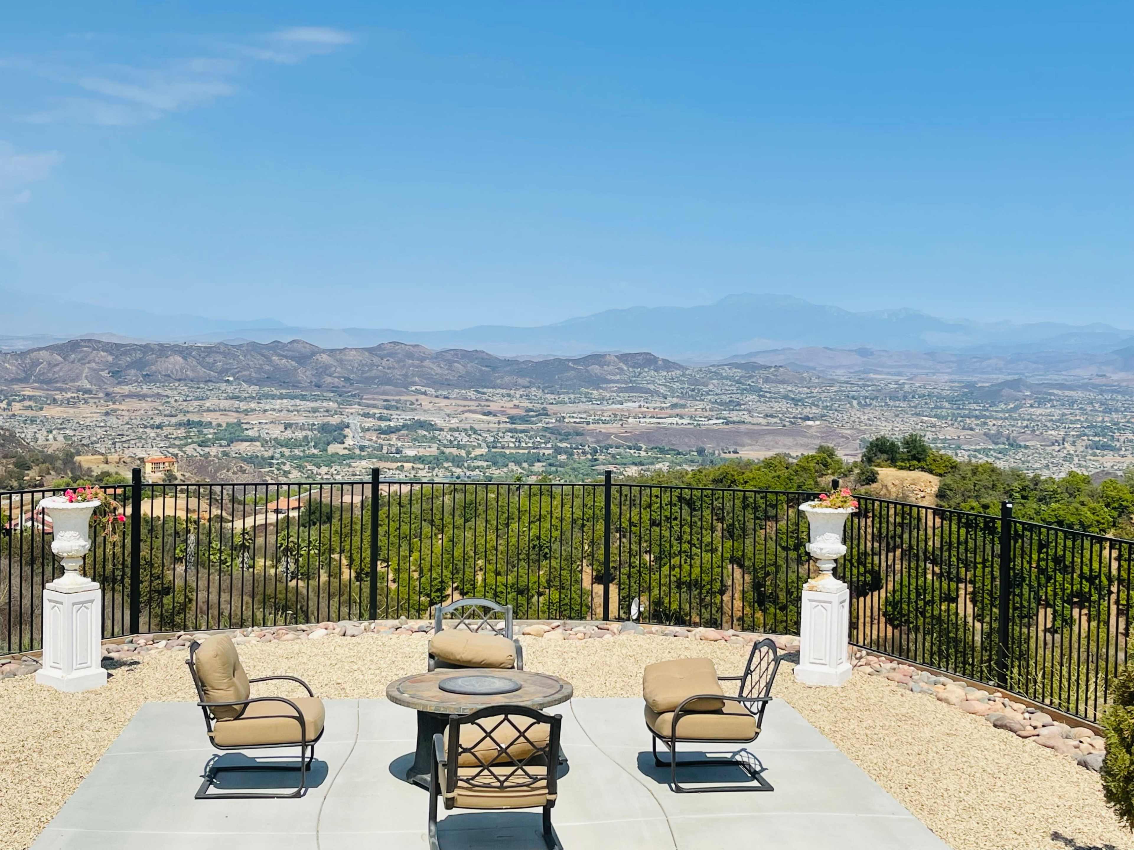 A patio with chairs and a table overlooking a mountainous landscape.