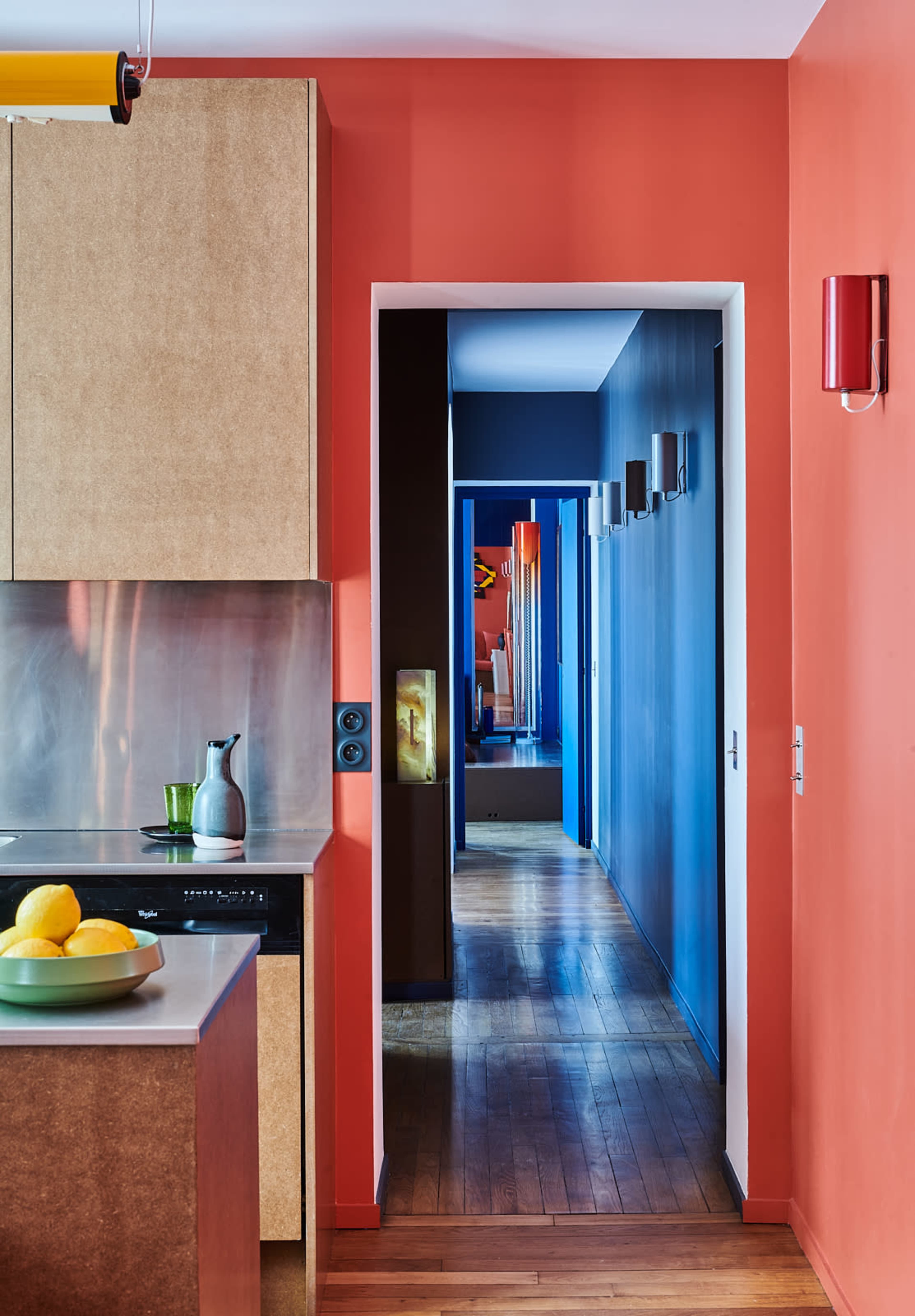 A modern kitchen with a countertop and a view of a brightly colored hallway extending beyond it.