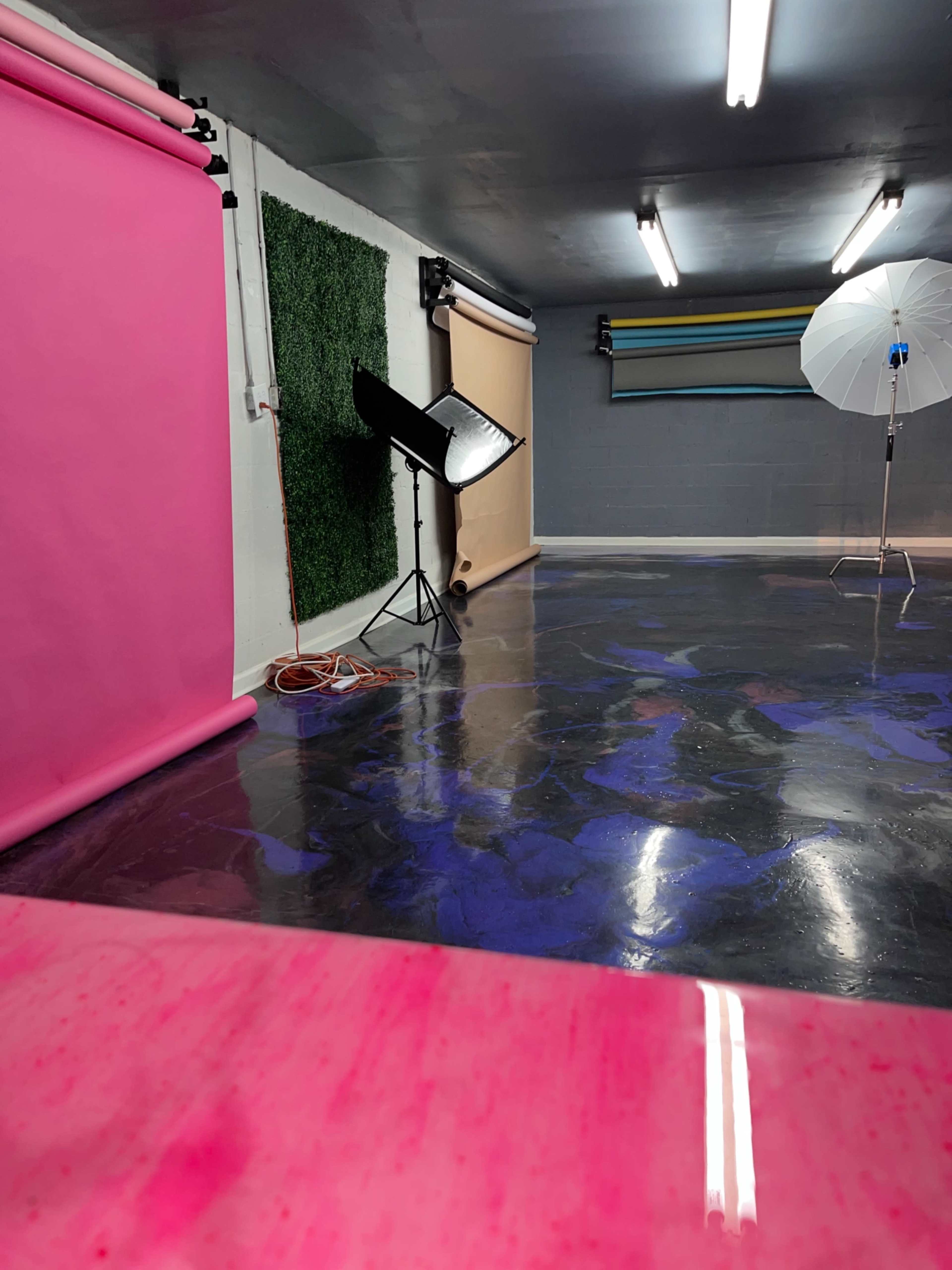 A photography studio features various backdrops, lighting equipment, and painted flooring.