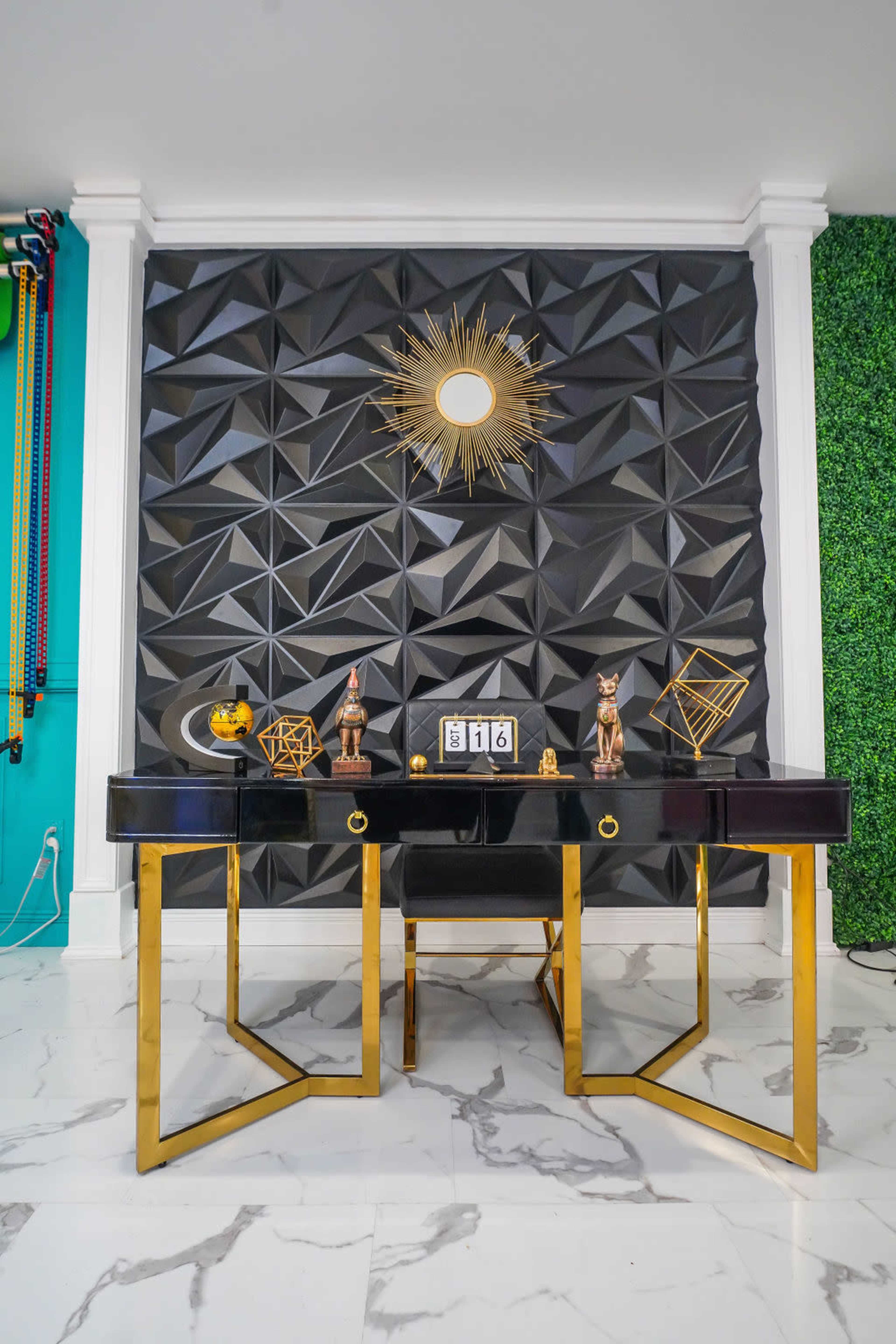 A black and gold desk is positioned against a textured black wall, adorned with decorative items and a clock displaying the time.