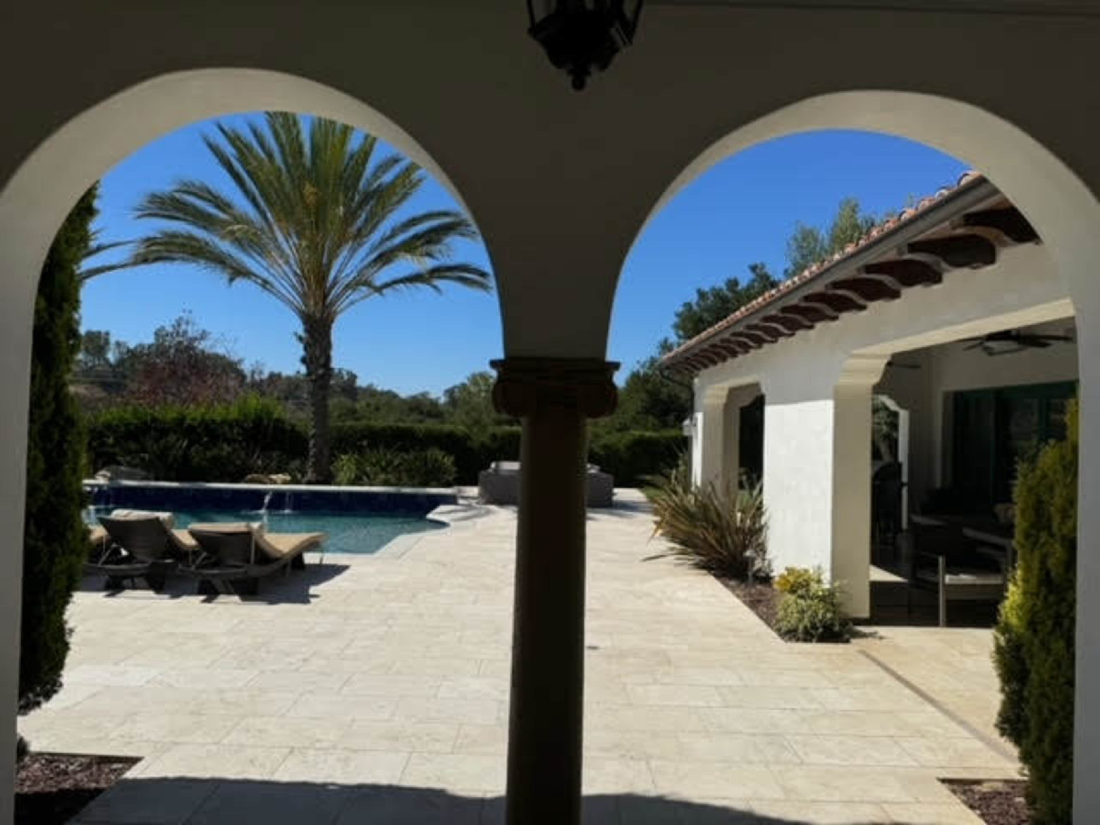 Mediterranean outdoor space with separate garden courtyard and backyard with a pool and spa.  It is surrounded by pal trees, olive trees, fruit trees, cypress trees.  Expansive and open back yard with endless views. Image in Turtle Rock, IRVINE, CA