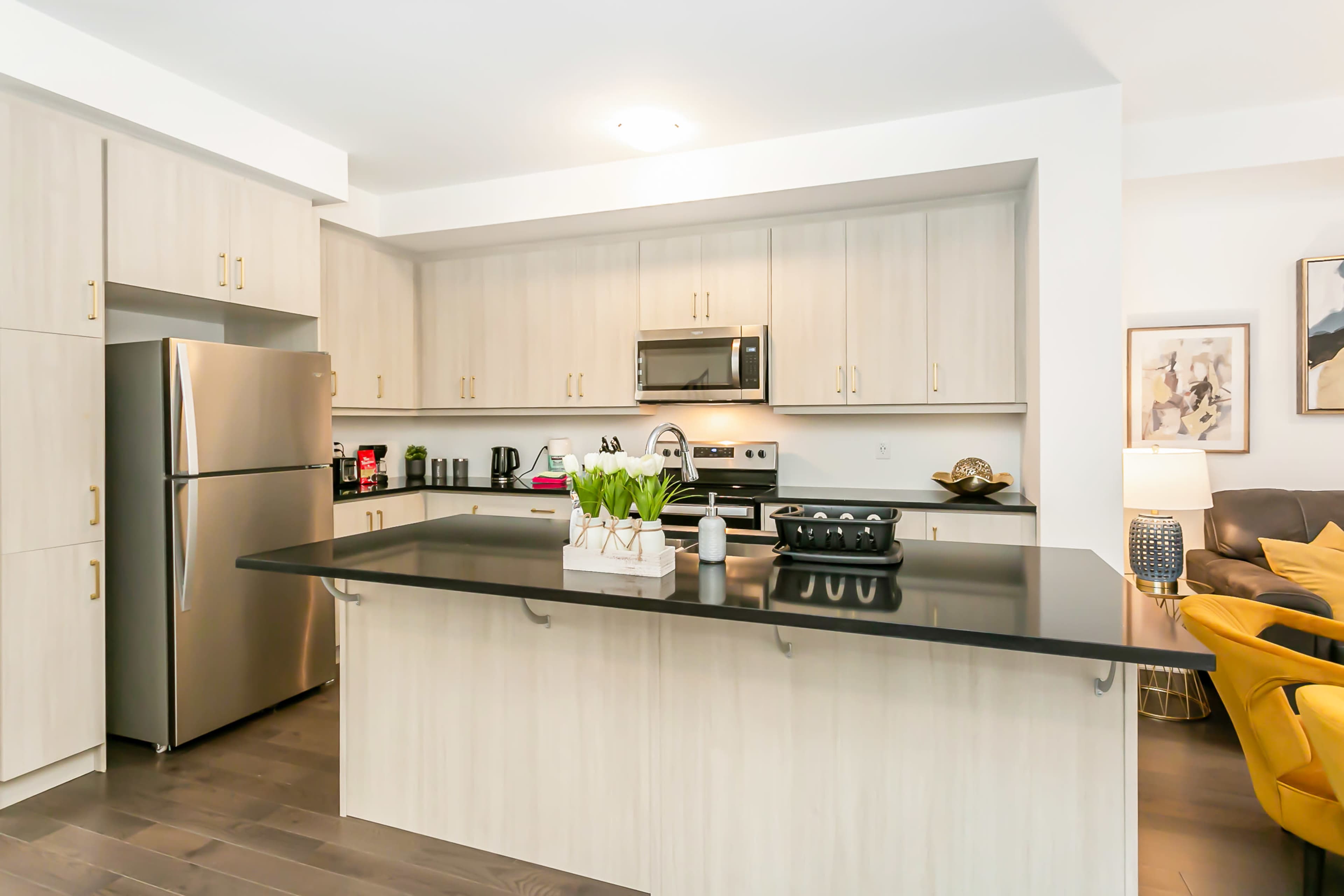 A modern kitchen features light-colored cabinetry, stainless steel appliances, and a dark countertop with a central island.