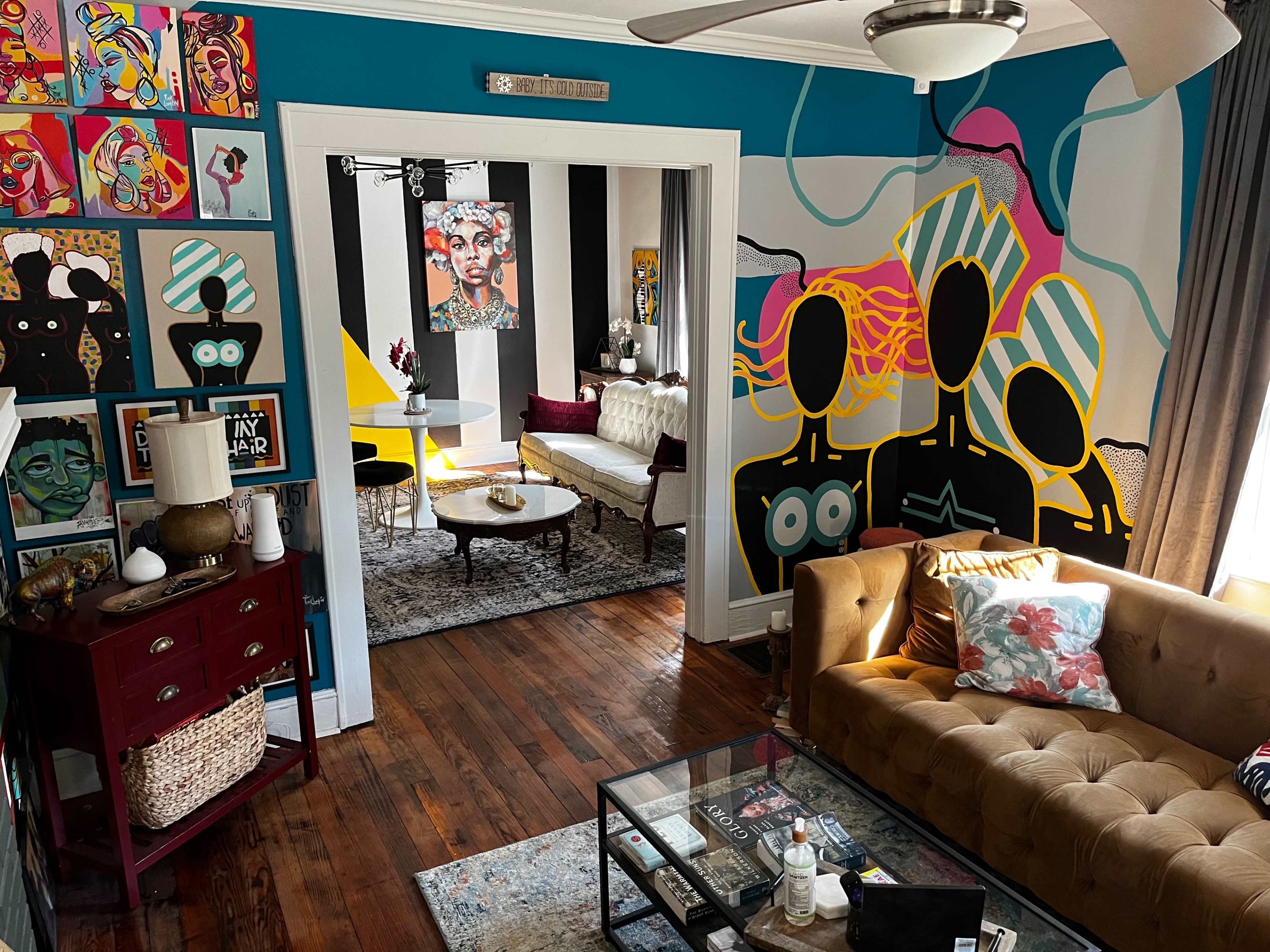 A vibrant living space with colorful artwork on the walls, a tufted brown sofa, and a stylish coffee table.
