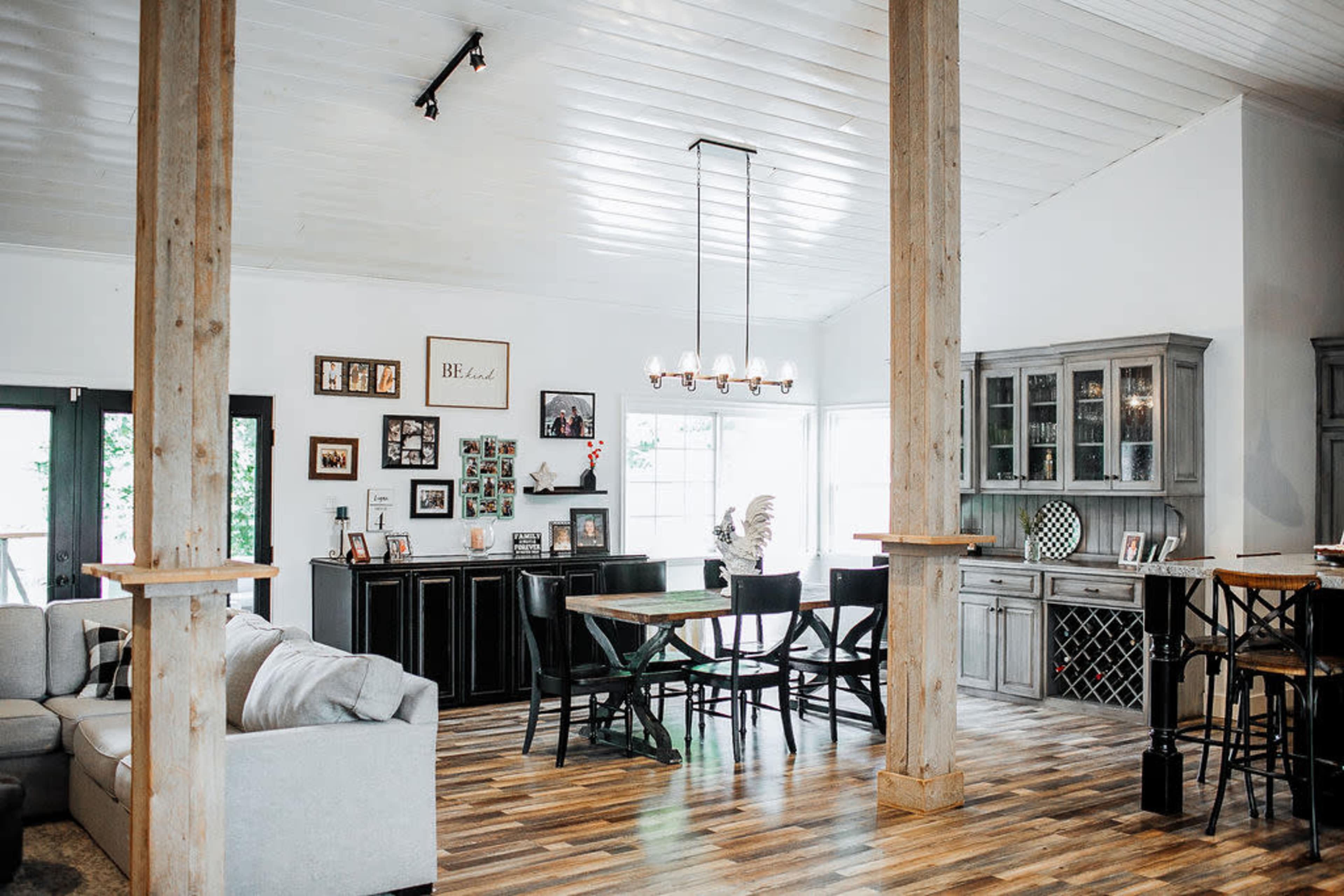 A spacious living area with a combination of seating, a dining space, and a display cabinet, featuring large windows that allow natural light to fill the room.