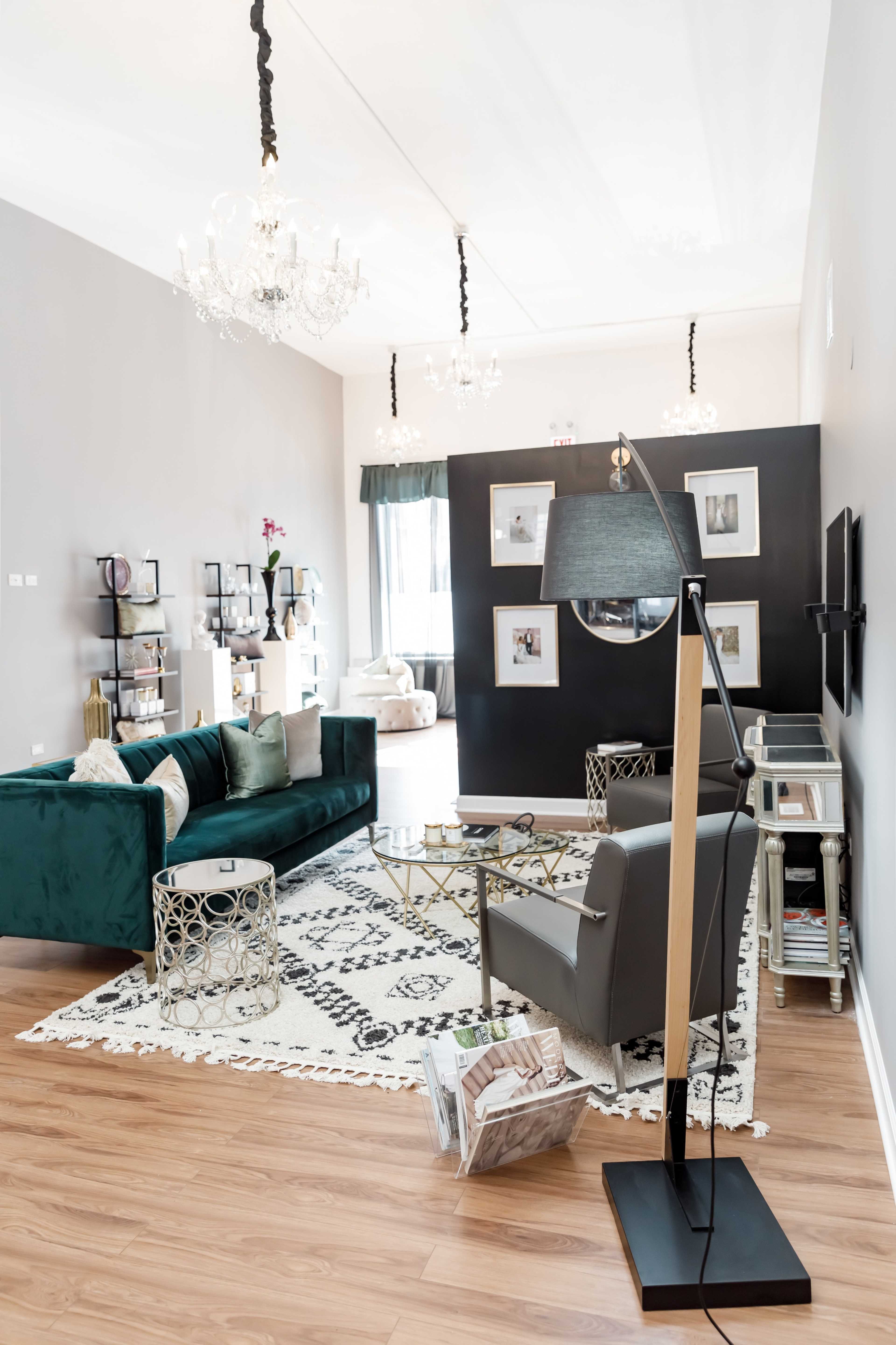 A modern living room featuring a green velvet sofa, a geometric coffee table, a floor lamp, and decorative wall art against gray walls.