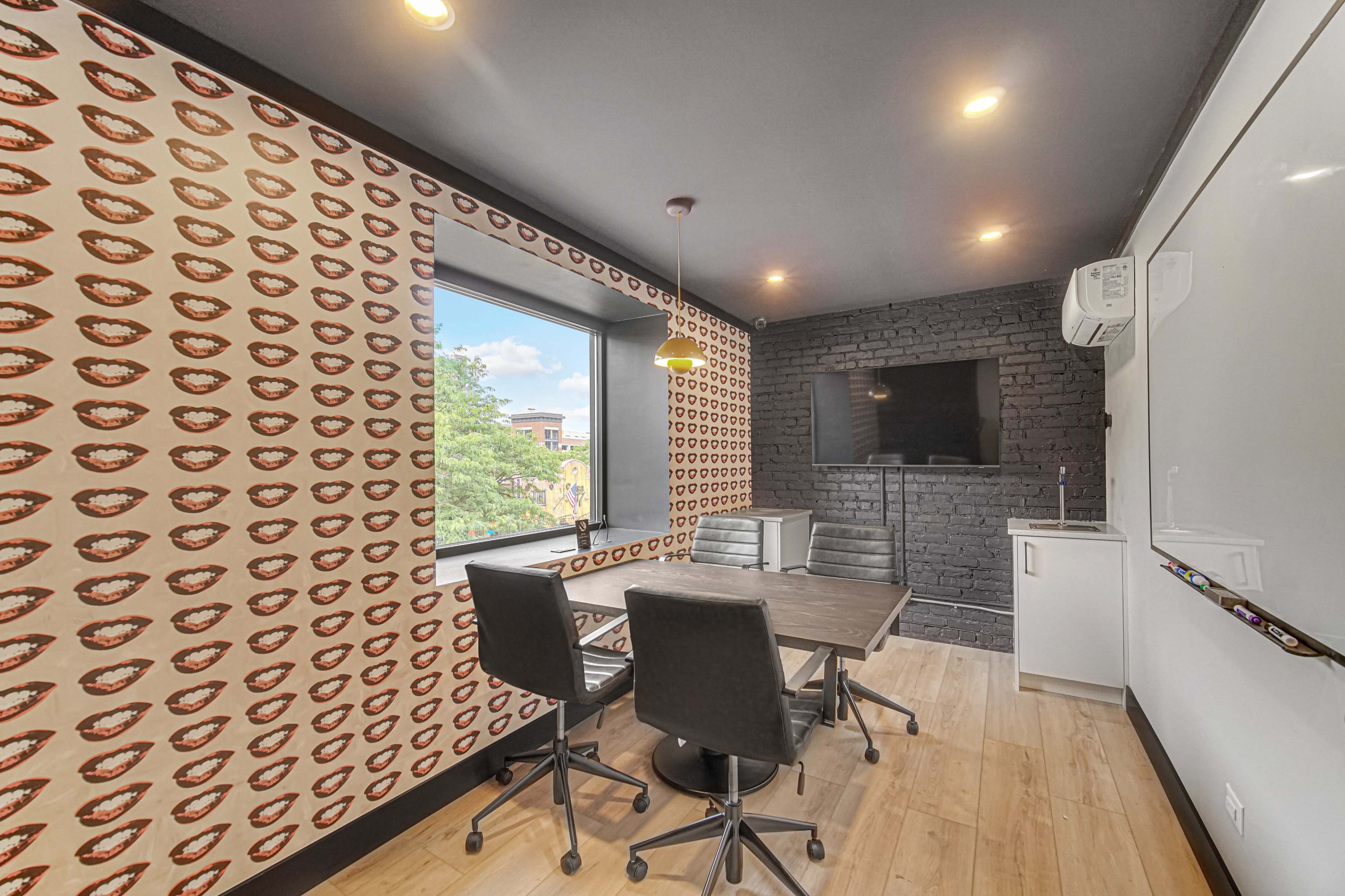 The image shows a modern conference room with a table and chairs, featuring bright patterned wallpaper and large windows.