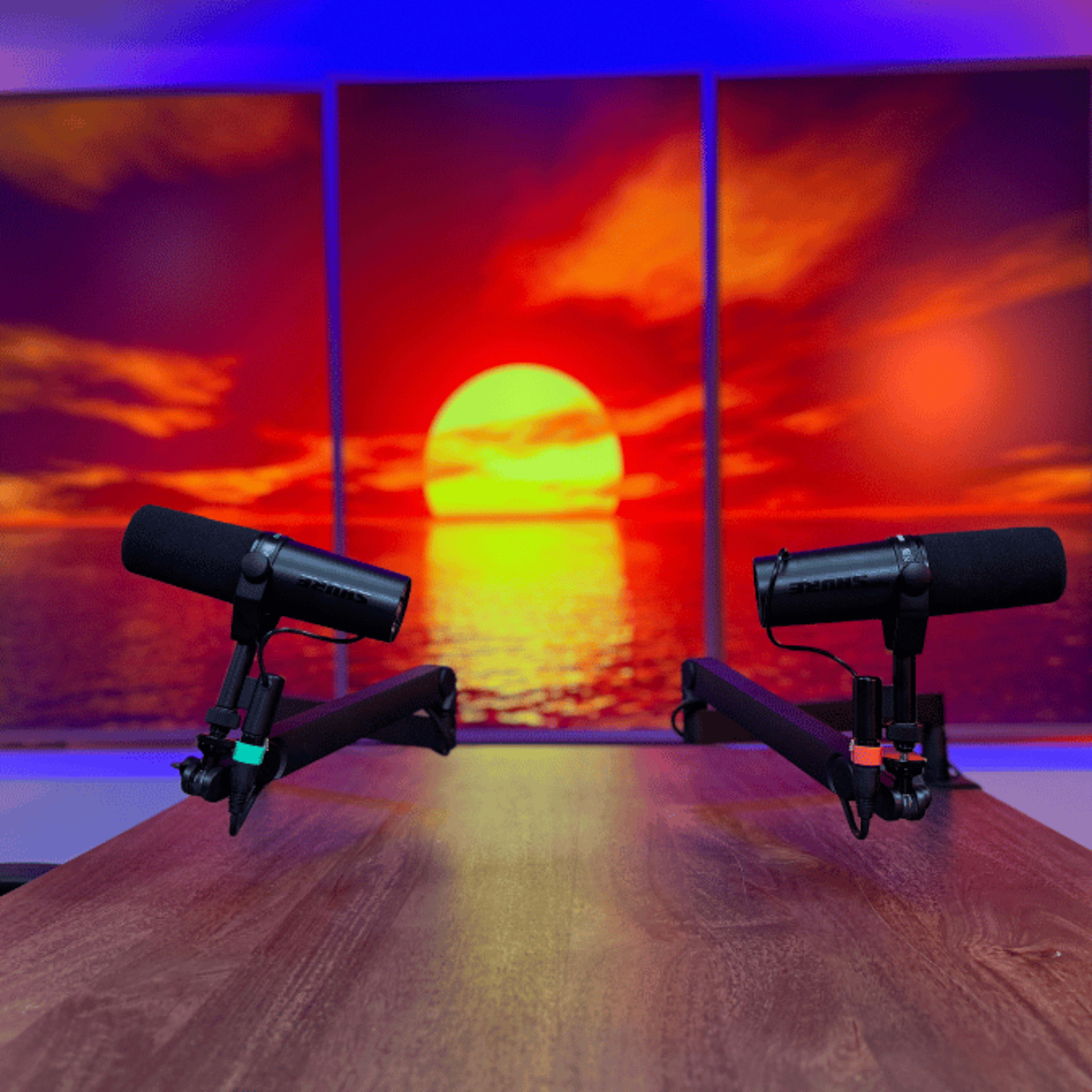 The image features two microphones mounted on stands positioned on a wooden table, with a vibrant sunset backdrop dominated by a large sun over a water surface.