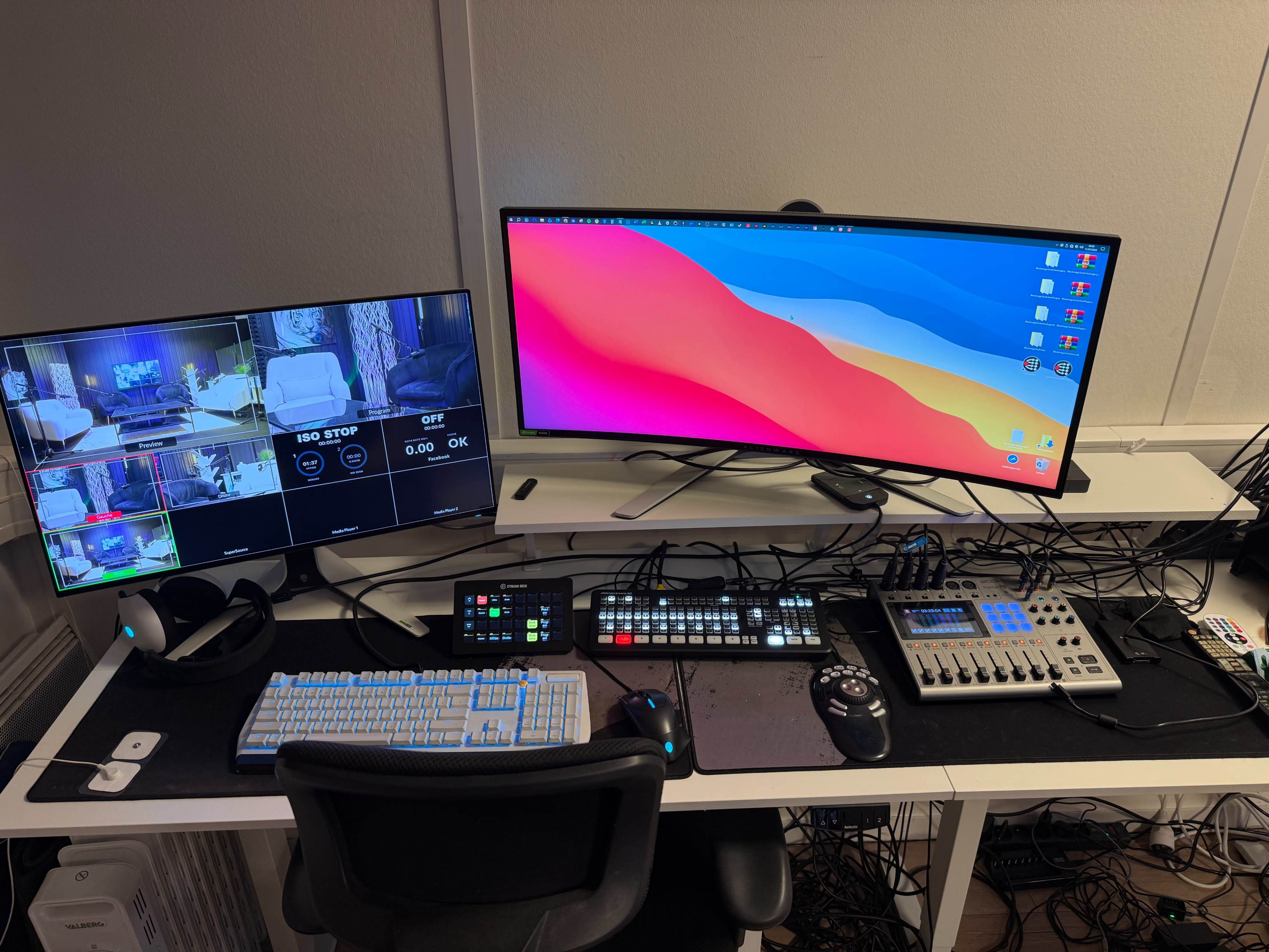The image shows a workspace equipped with multiple computer monitors, a keyboard, a control panel, and various cables arranged on a desk.