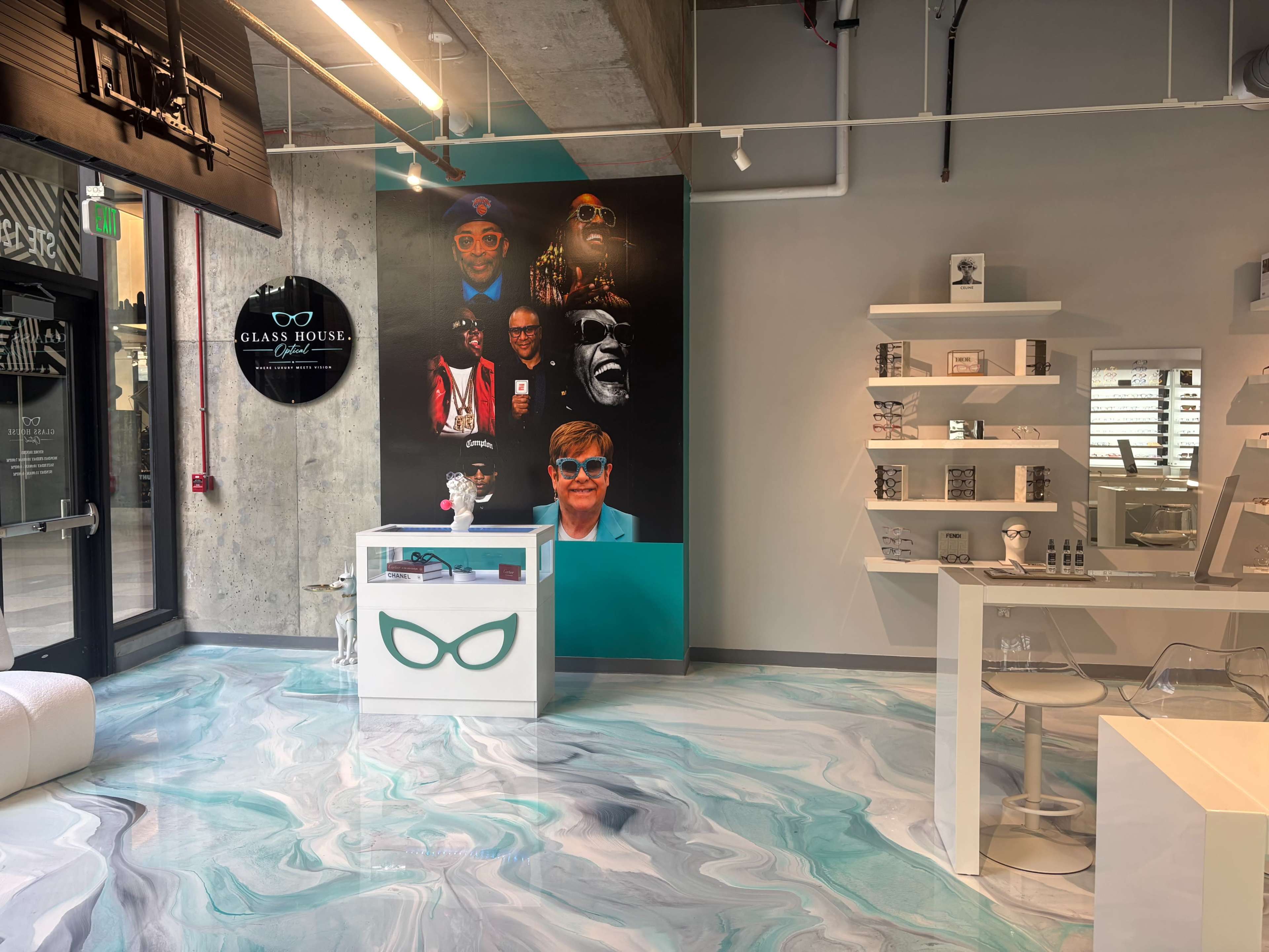 The image shows a modern retail space featuring a colorful mural of various faces on the wall, a display counter with a unique design, and minimalist shelving units.