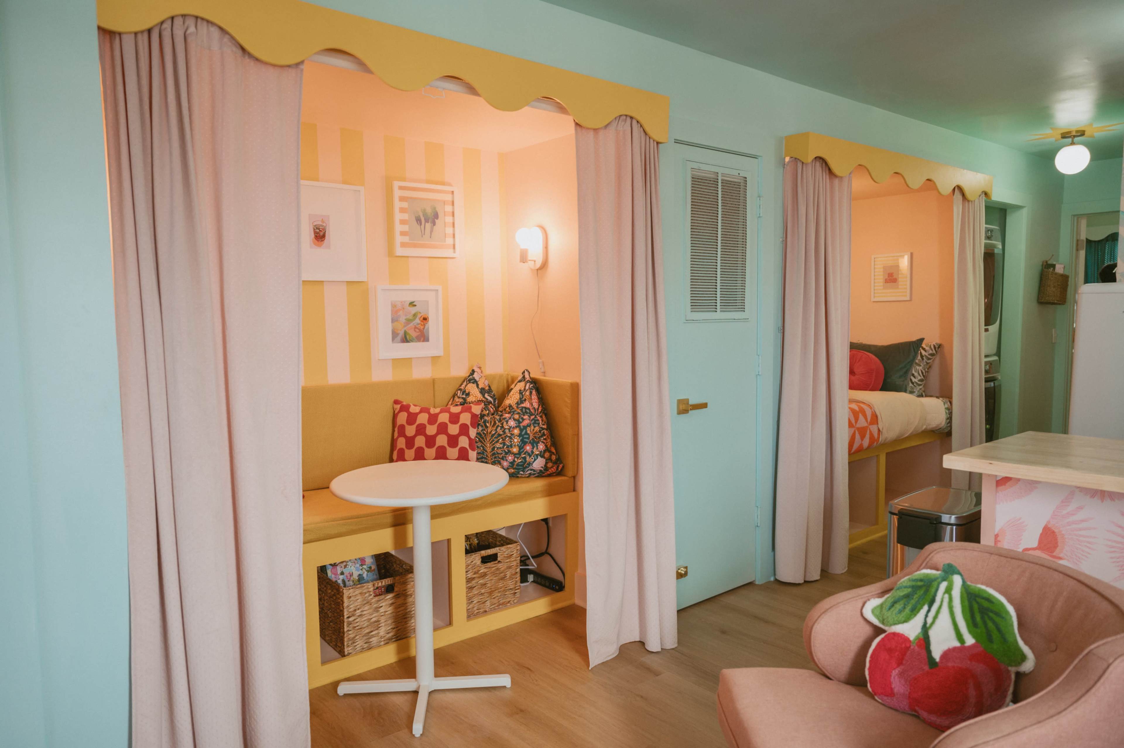 A brightly colored room divided into two distinct areas with plush seating, decorative pillows, and light curtains.