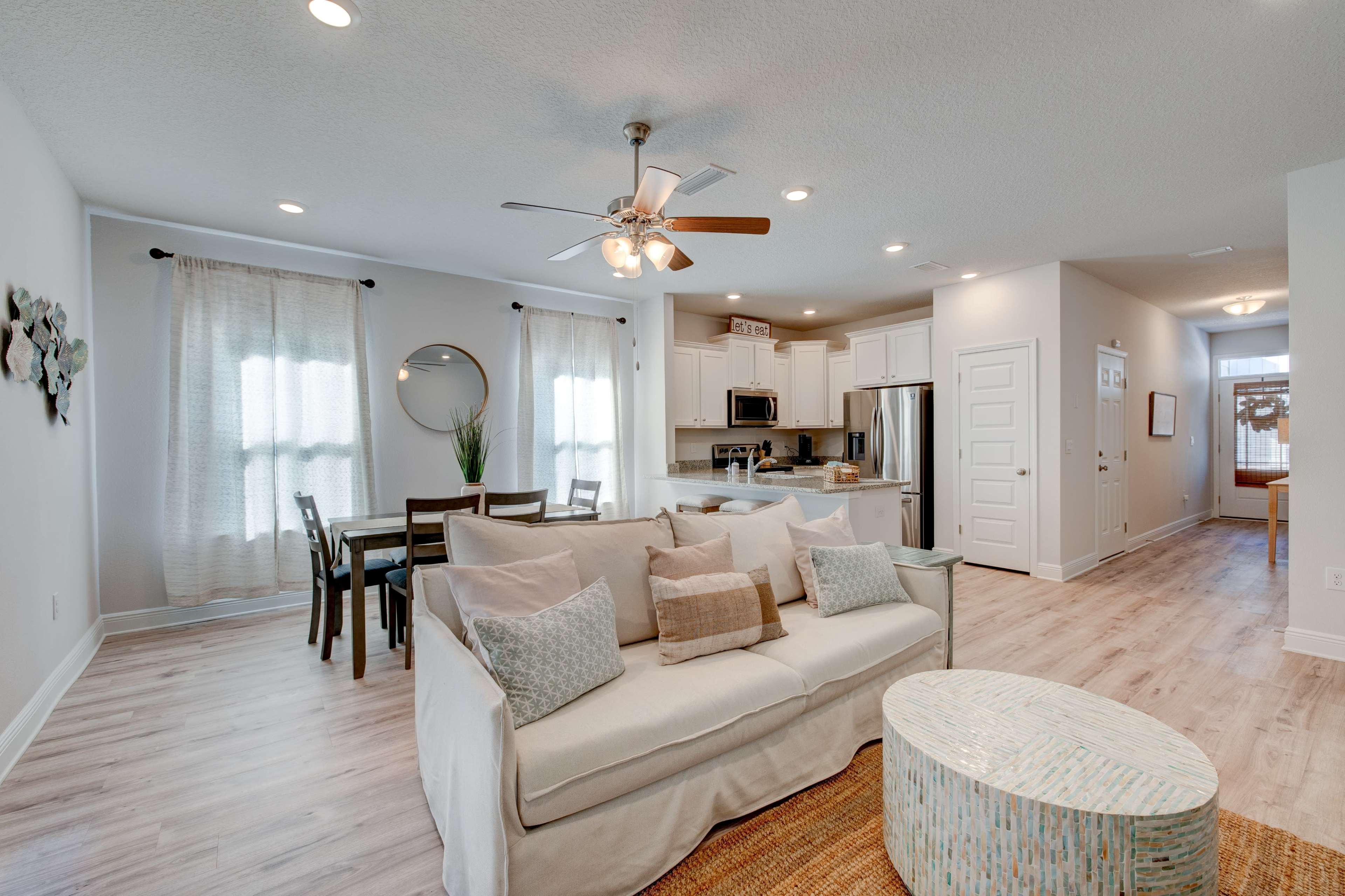A comfortable living area features a sofa, dining table, and a kitchen in an open-concept layout with neutral decor.