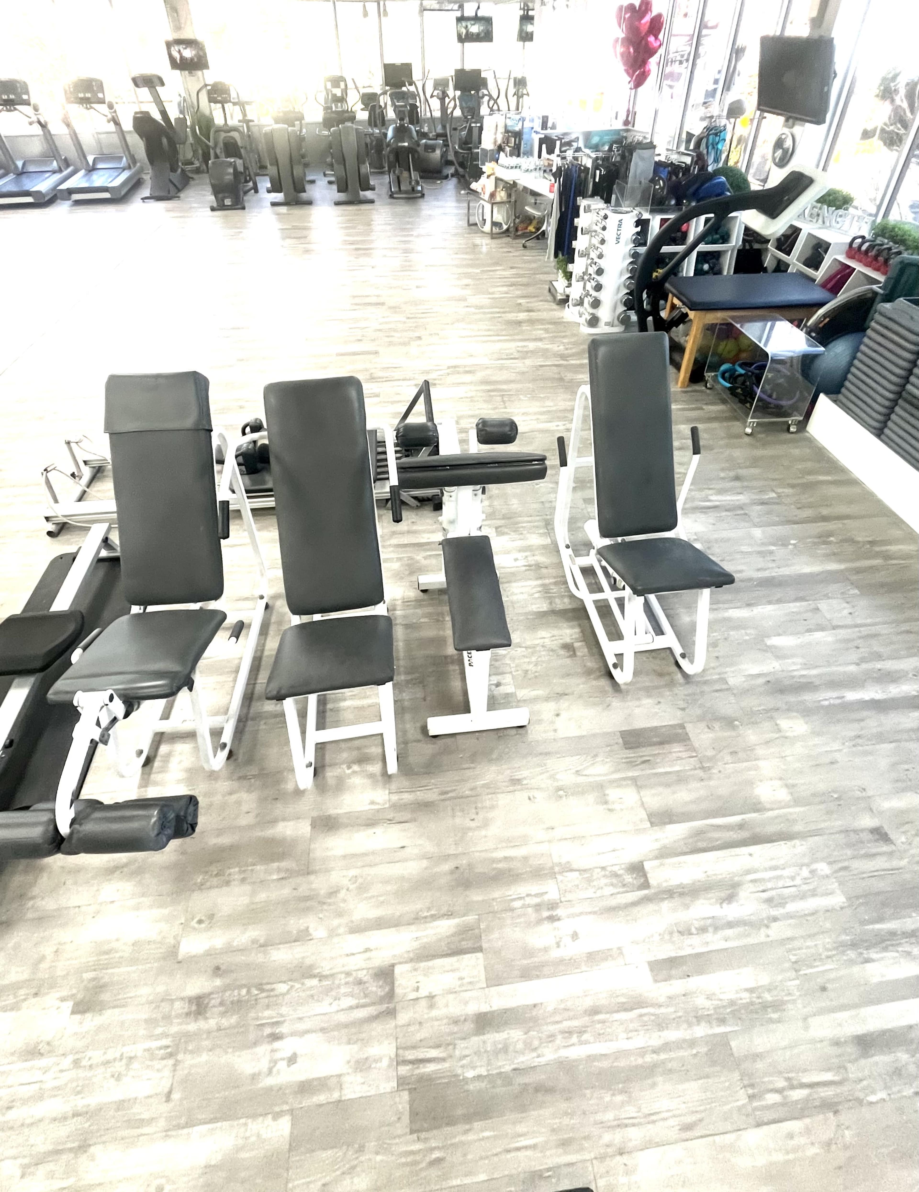 A gym interior with exercise equipment, including two benches and various cardio machines in the background.