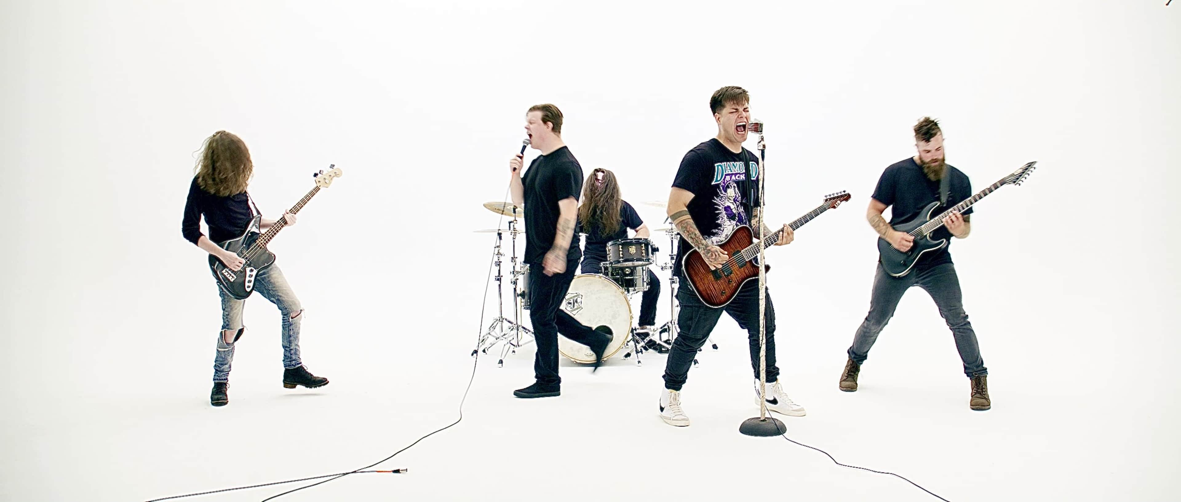 A band performs on stage with instruments against a white background.