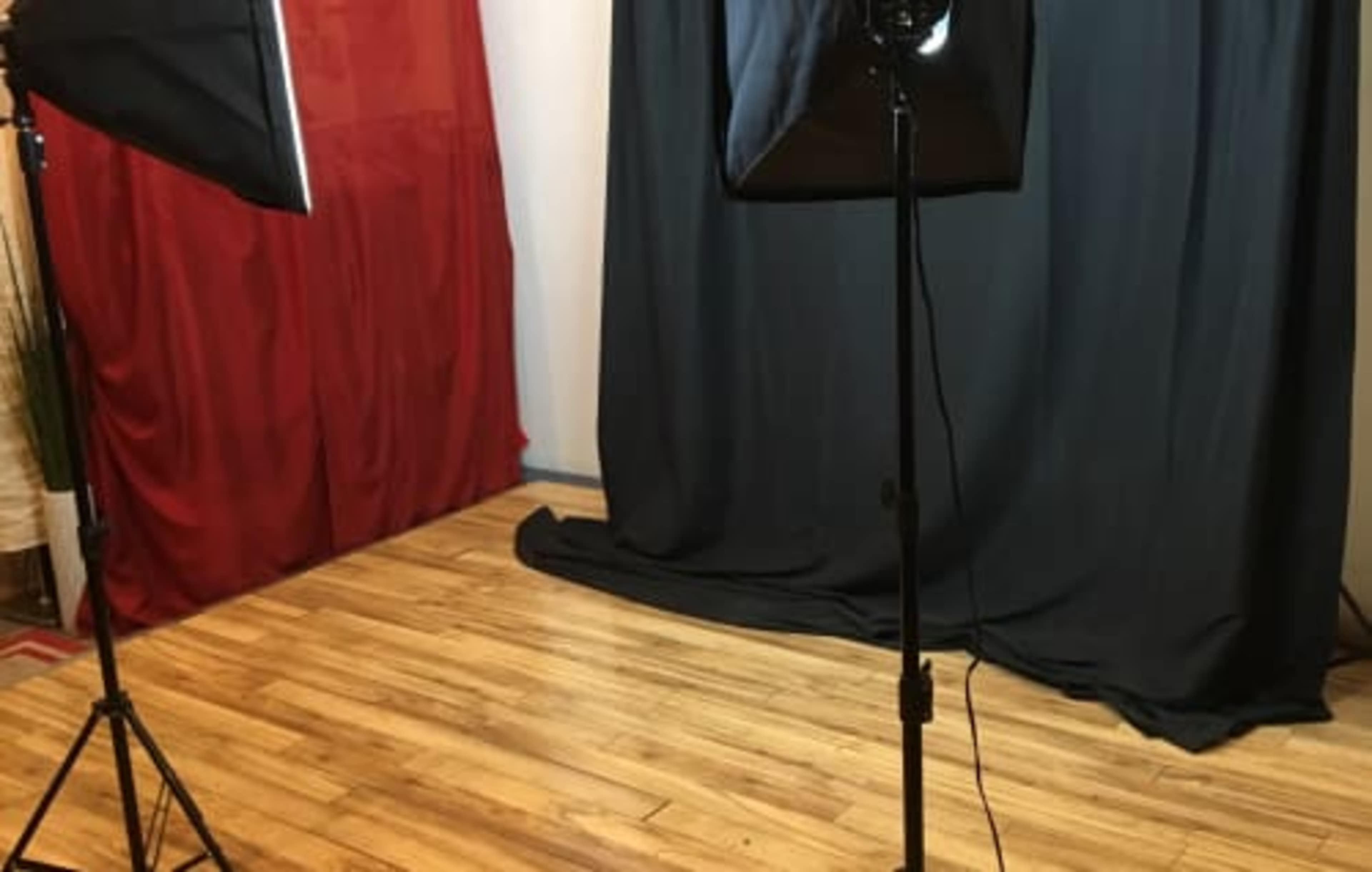A photography setup with lighting equipment and a black backdrop on a wooden floor.