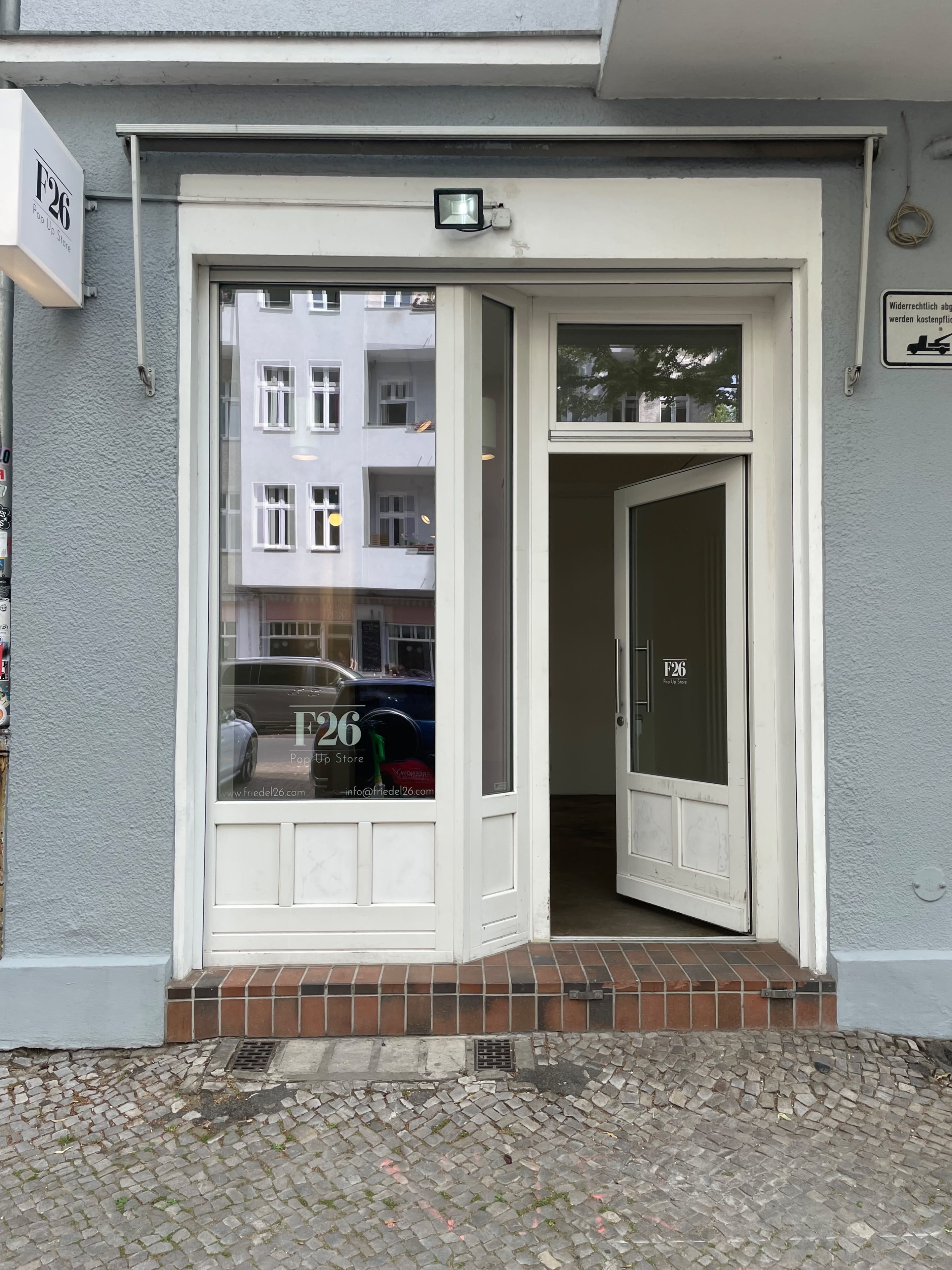 The image shows a storefront with large glass windows and a double door entrance, displaying the name "P26."