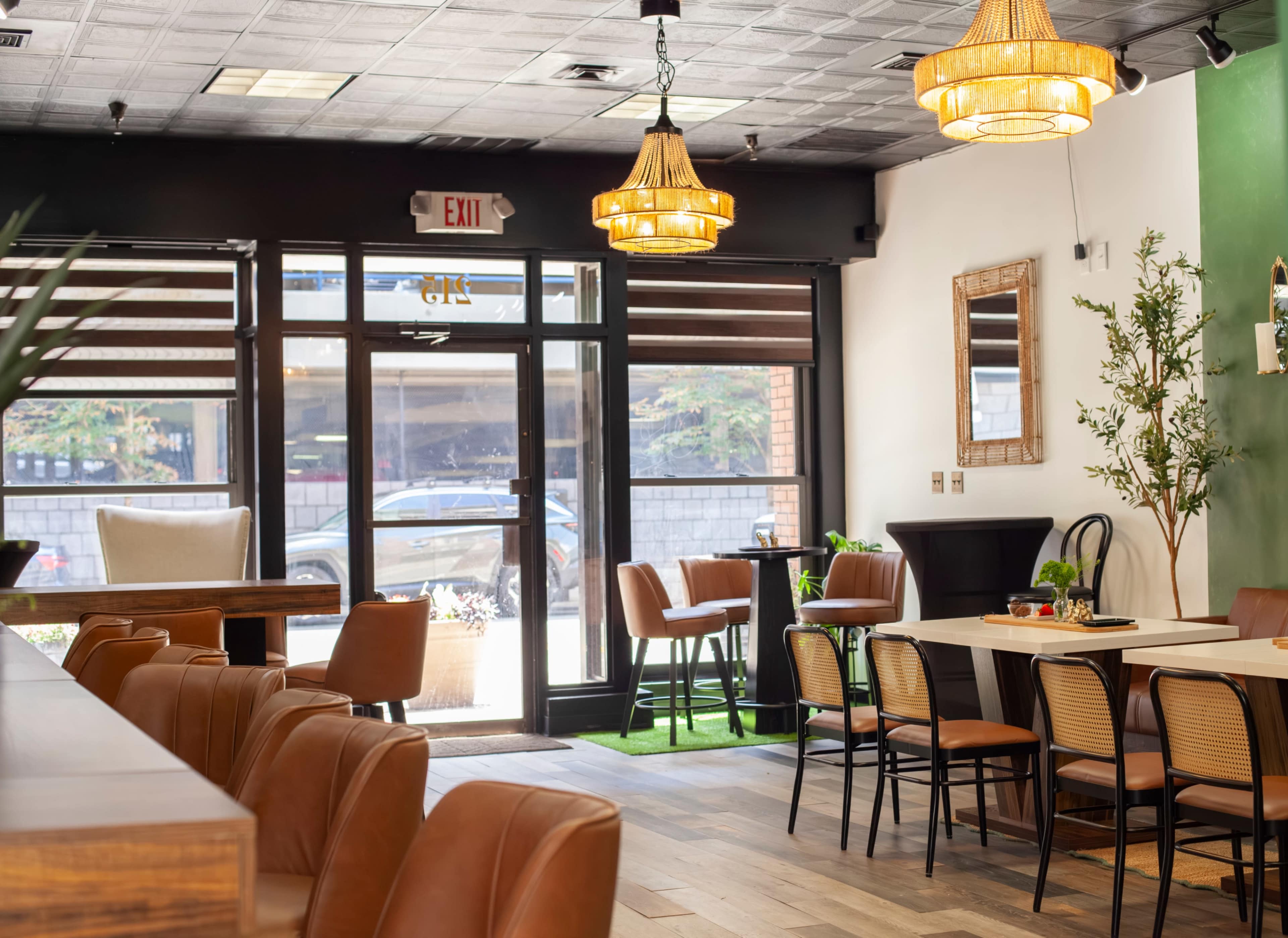 The image shows a modern café interior with wooden floors, stylish seating, and large windows that provide natural light.