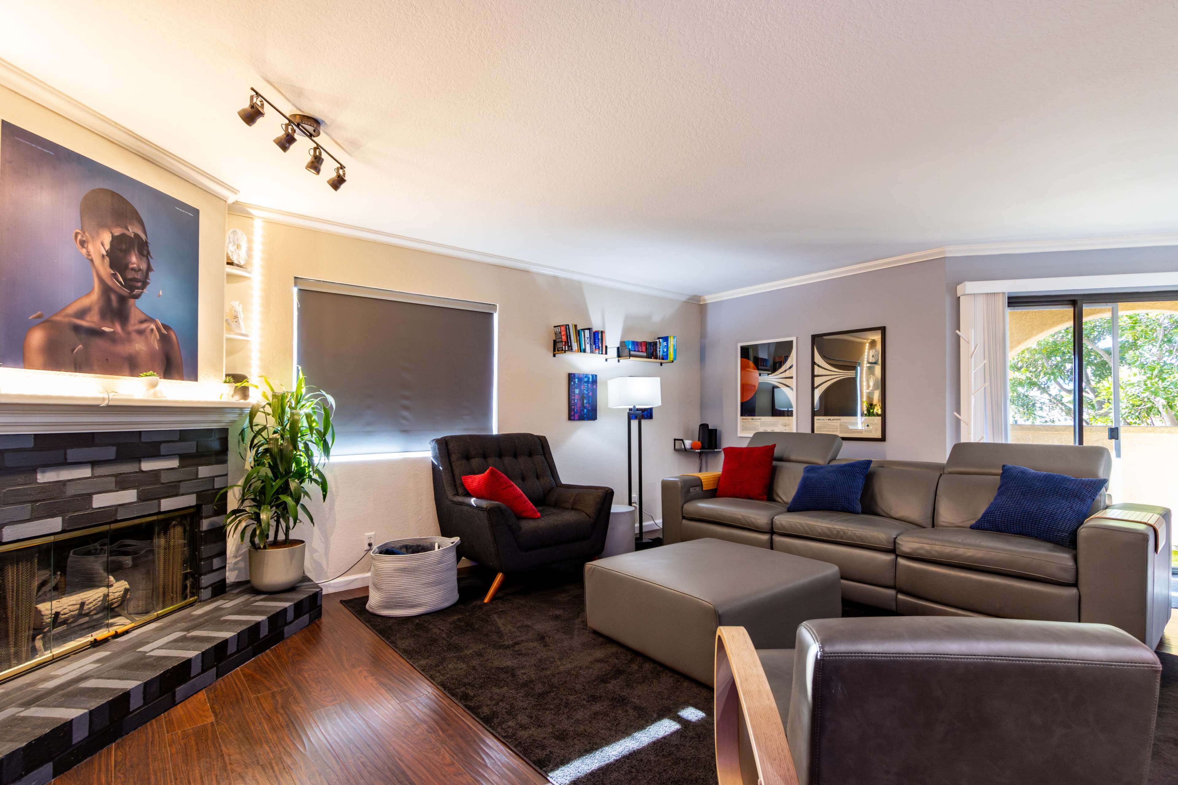A modern living room with a fireplace, black and gray sofas, a coffee table, and artwork displayed on the walls.