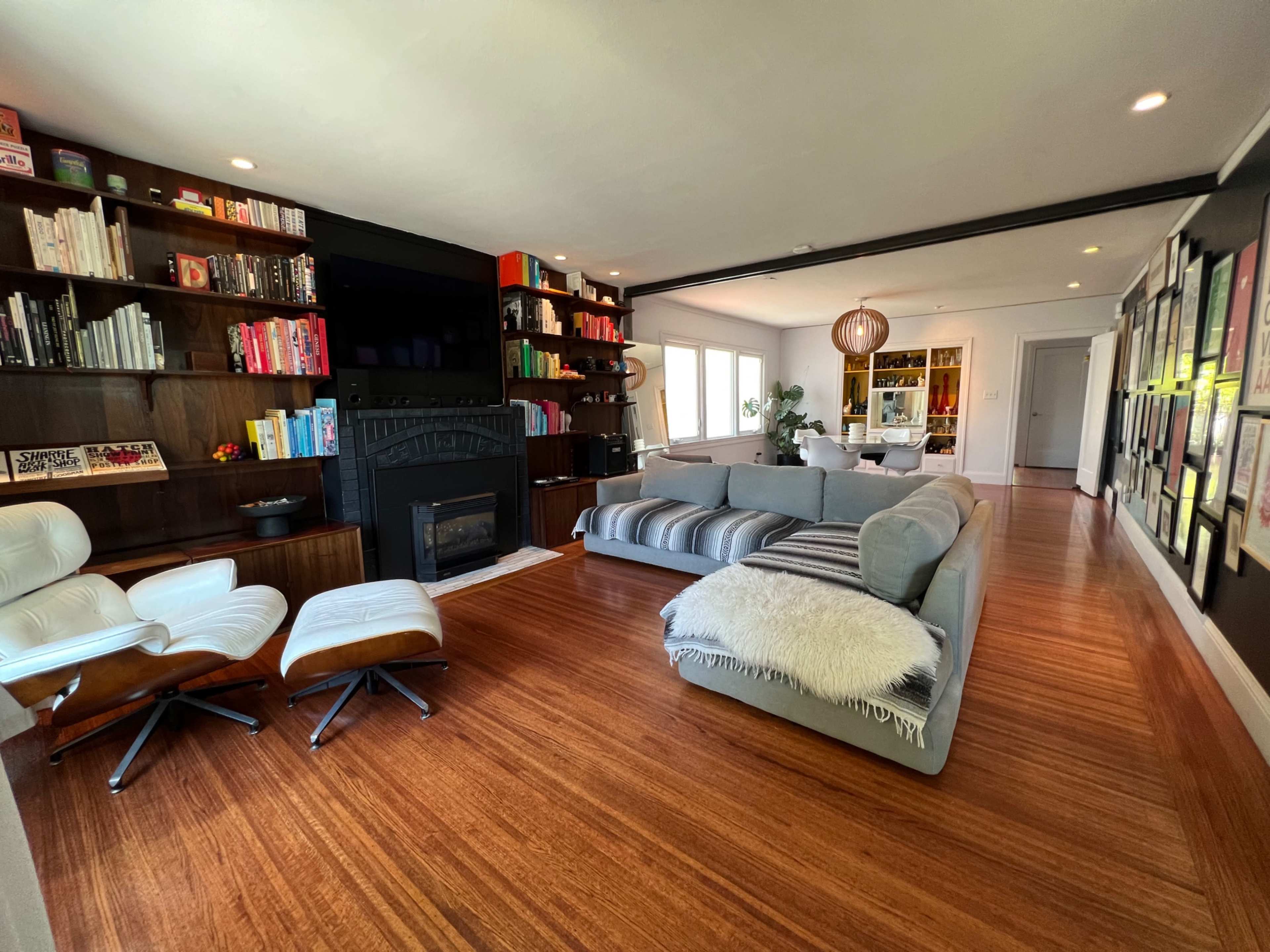 A modern living room with a large sectional sofa, a fireplace, and built-in bookshelves filled with books and decorative items.