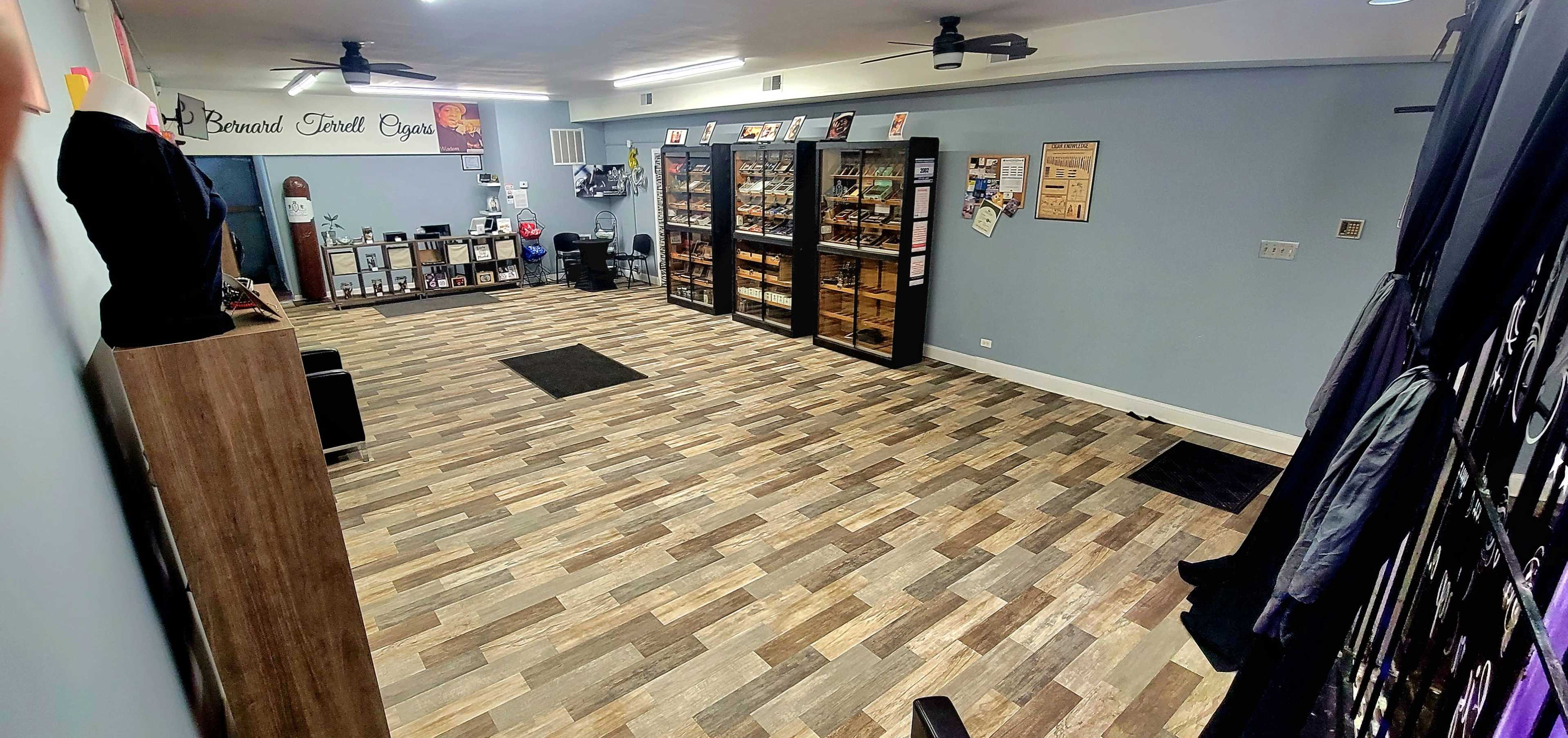 The image shows a spacious room with wooden flooring and two large display cases against the walls, filled with items, and various framed pictures and posters on the walls.