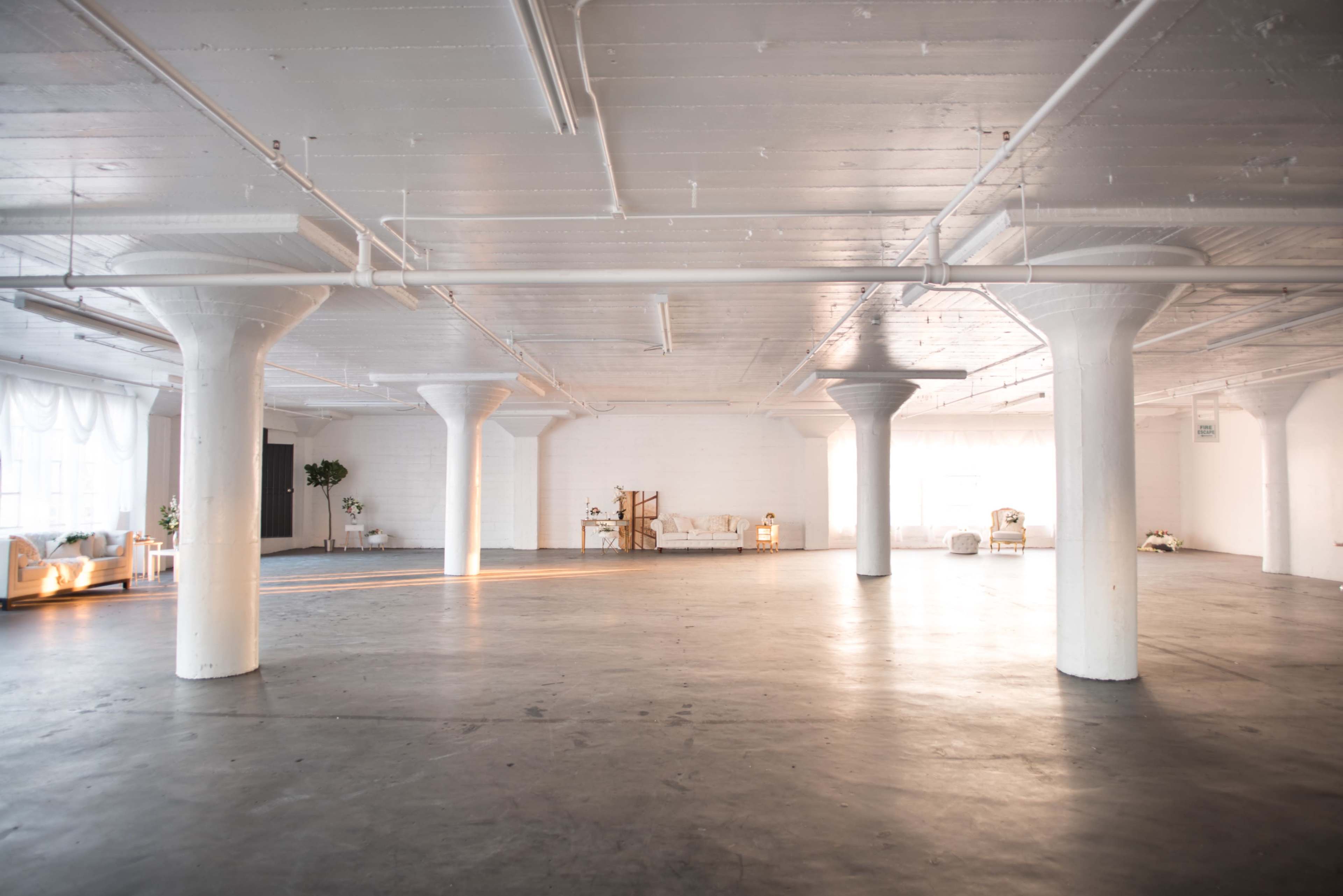 The image shows a spacious, well-lit industrial room with concrete floors and white columns.
