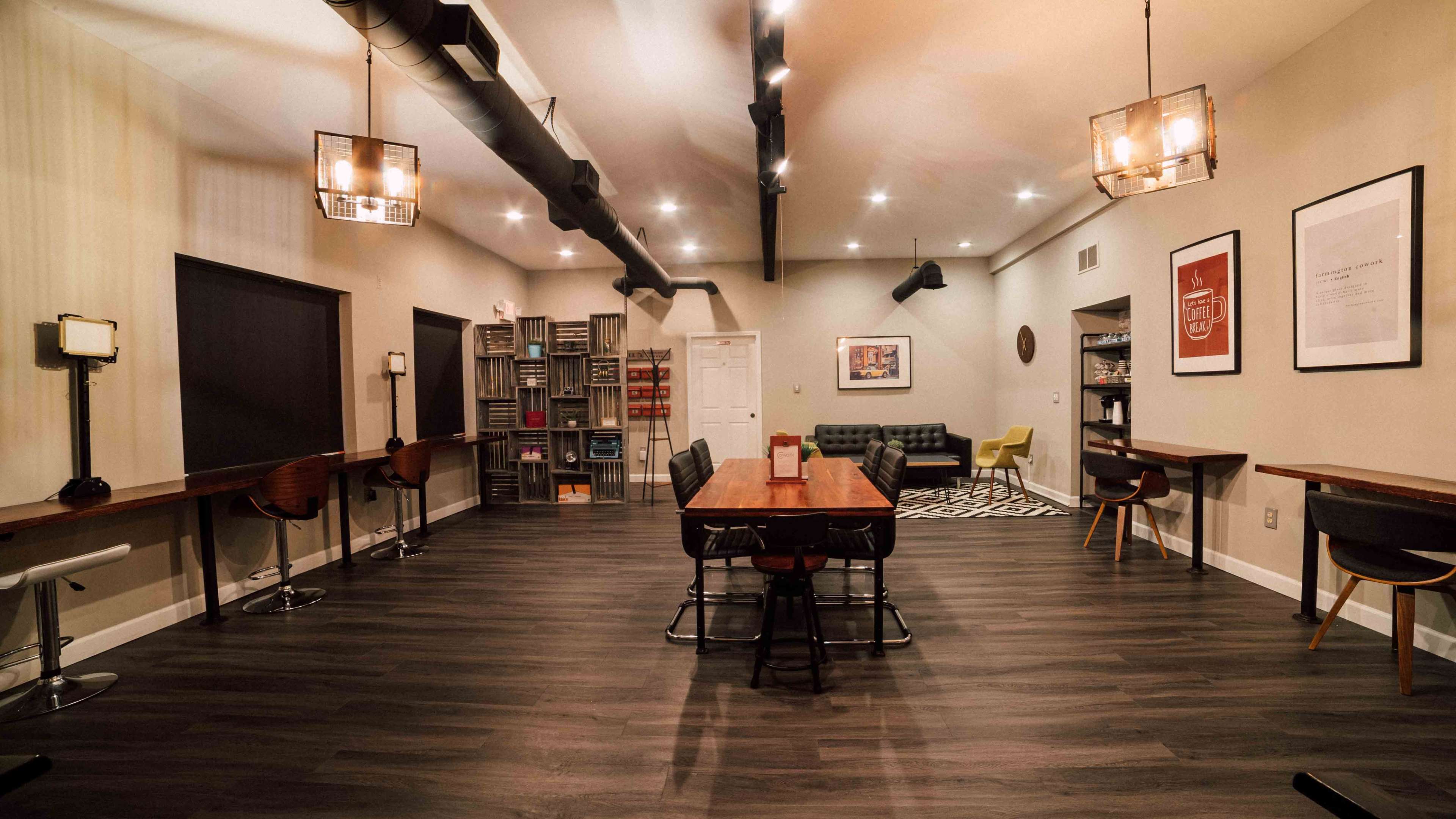 A spacious, modern room with wooden floors, several seating areas, and a long dining table in the center.
