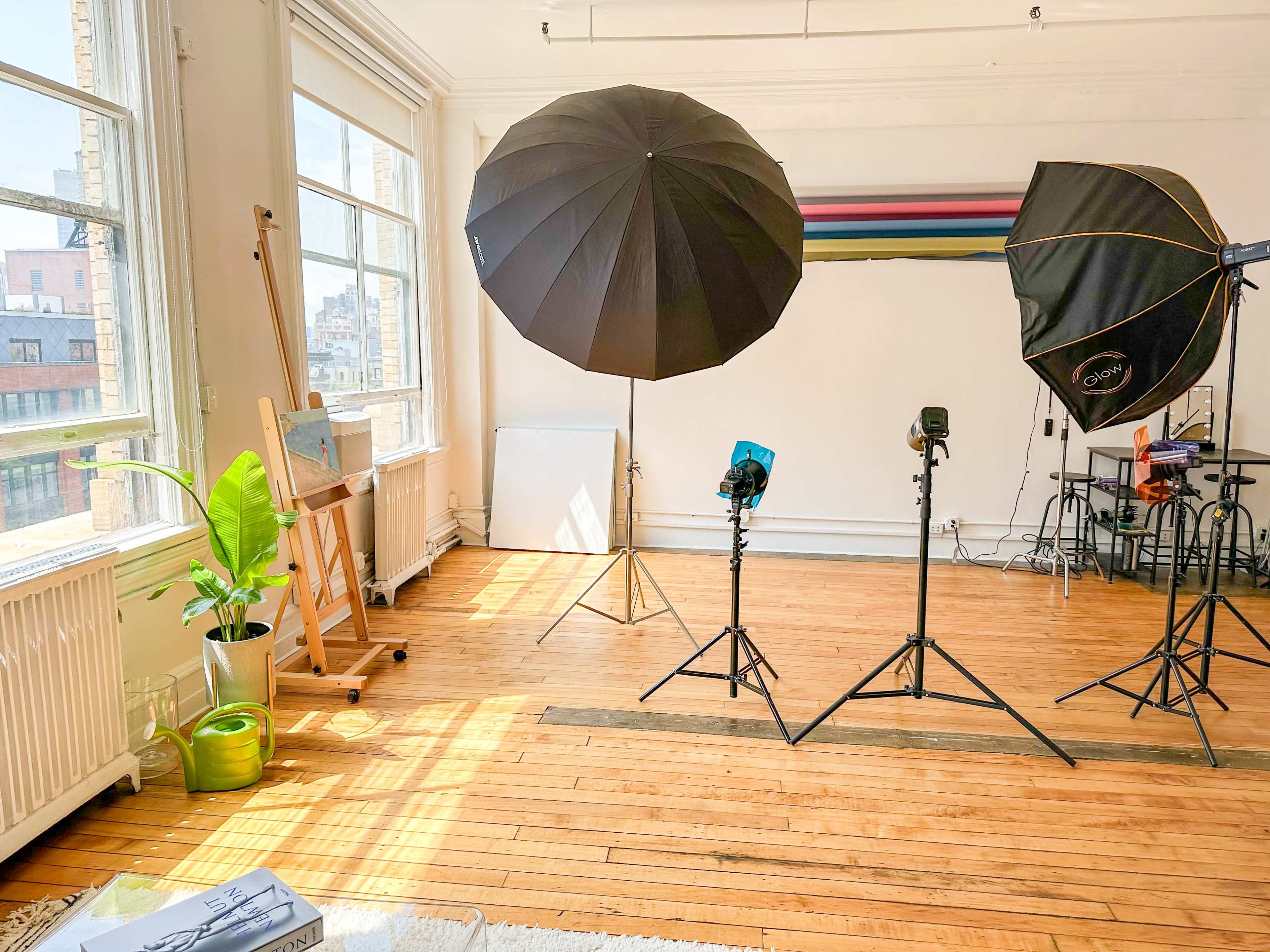 A bright photography studio with large softbox lights, an easel, and wooden floors.