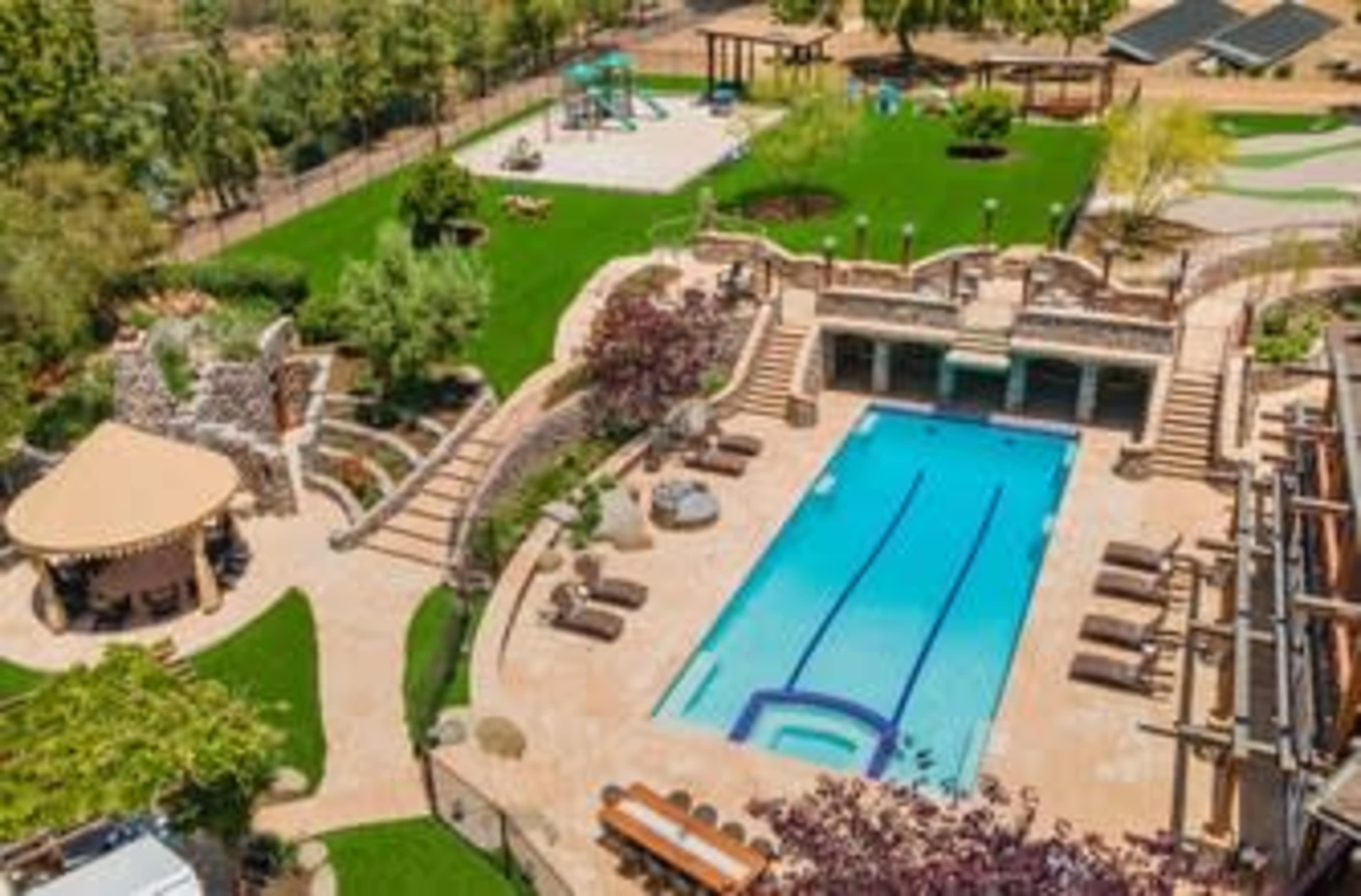 A well-designed outdoor area featuring a swimming pool, landscaped gardens, a playground, and various seating spaces.