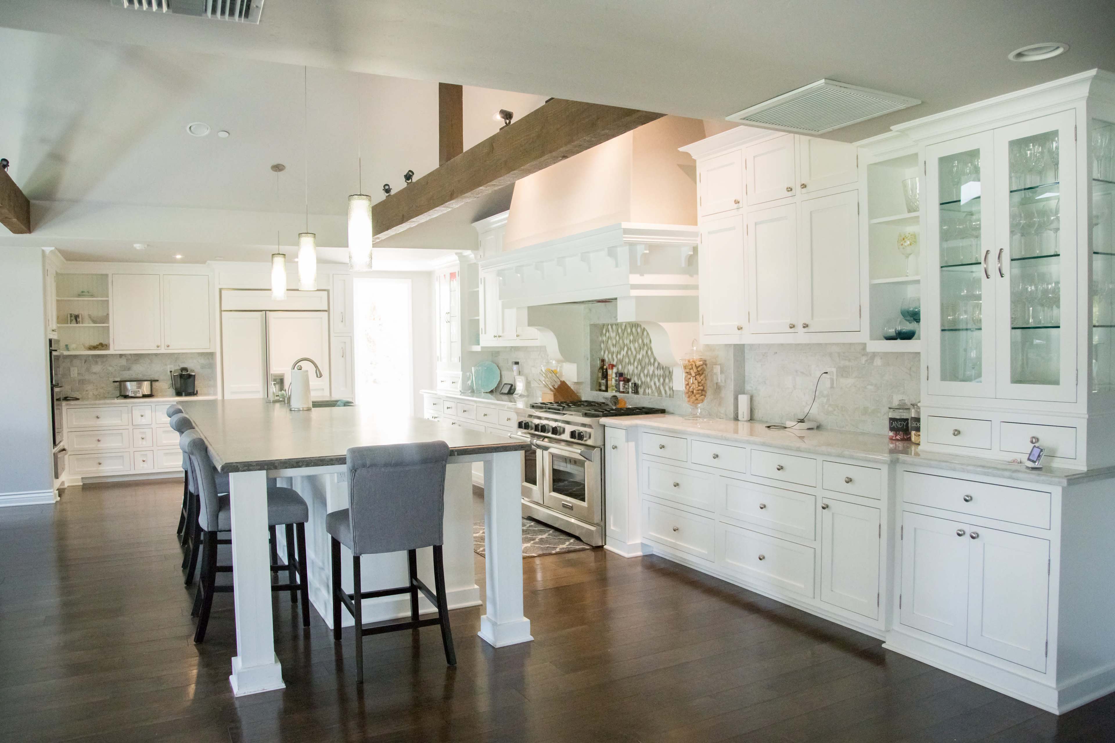 The kitchen features white cabinetry, a large island with bar seating, stainless steel appliances, and a spacious layout with hardwood flooring.