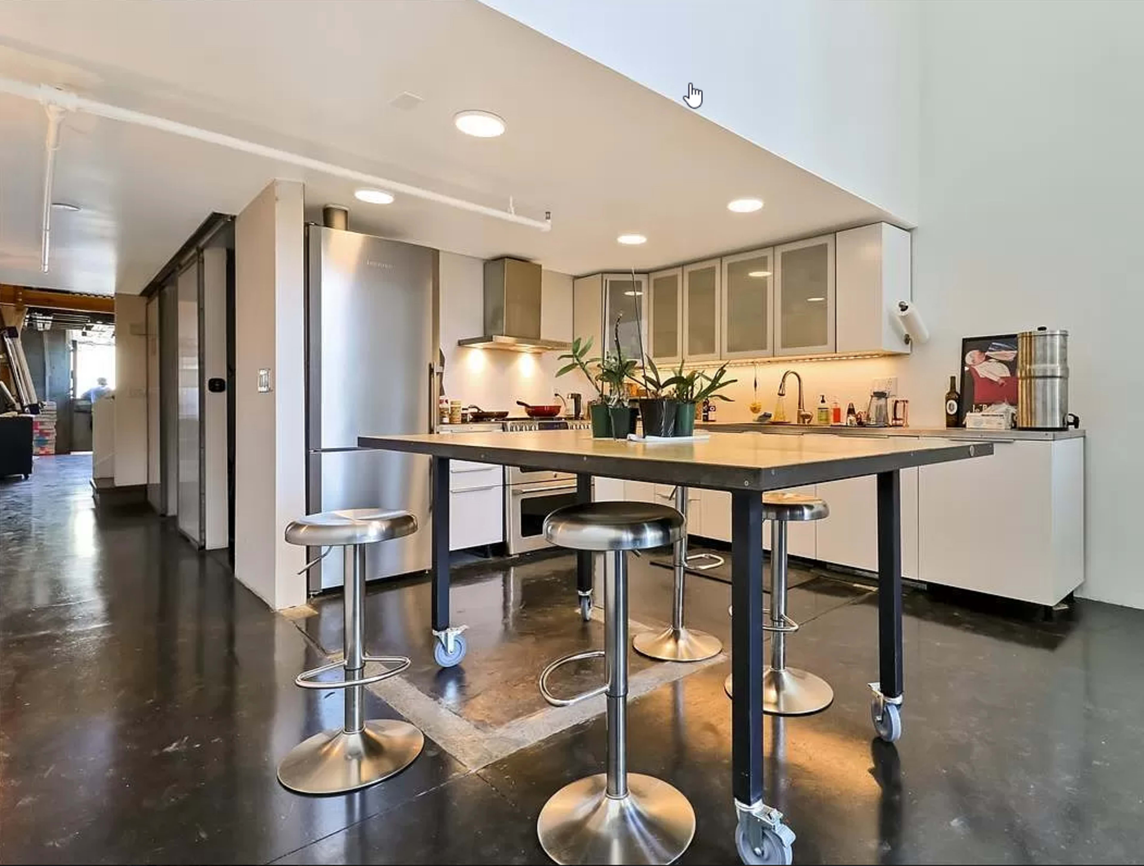 A modern kitchen featuring a large island with metallic stools, sleek cabinetry, and stainless steel appliances.