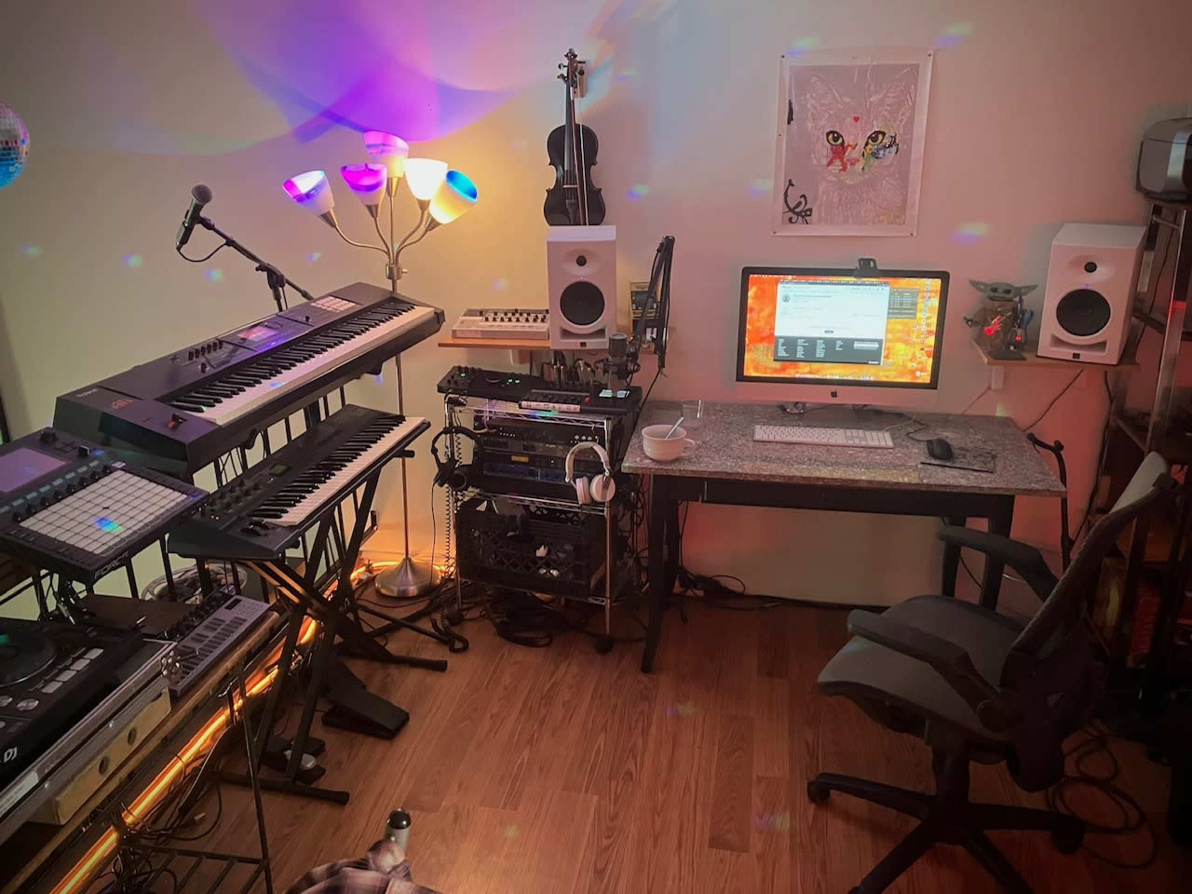 A home music studio with a keyboard setup, computer station, and various musical instruments, all illuminated by colorful lights.