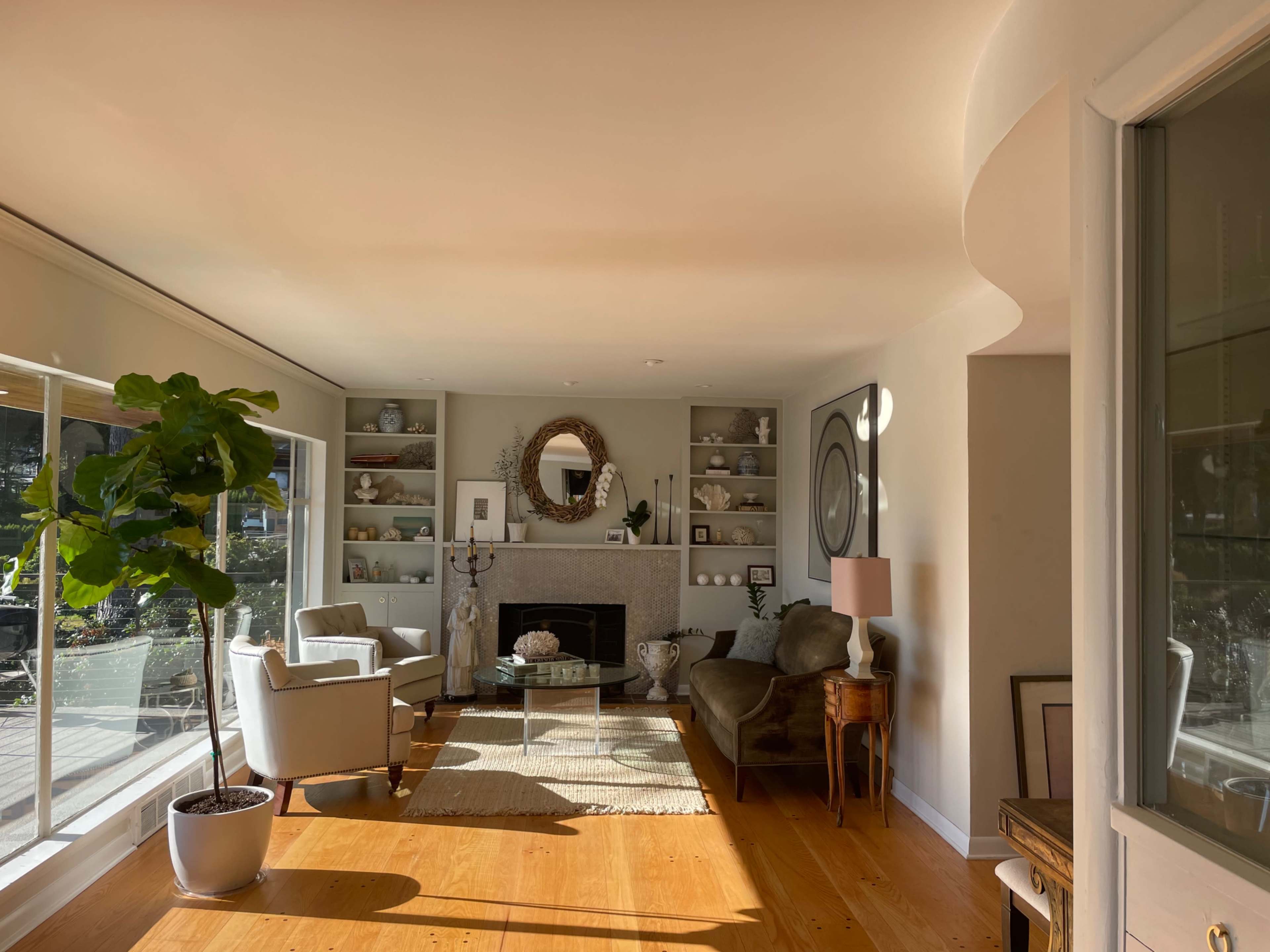 A living room features a fireplace, two armchairs, a sofa, and built-in shelves displaying decorative items.
