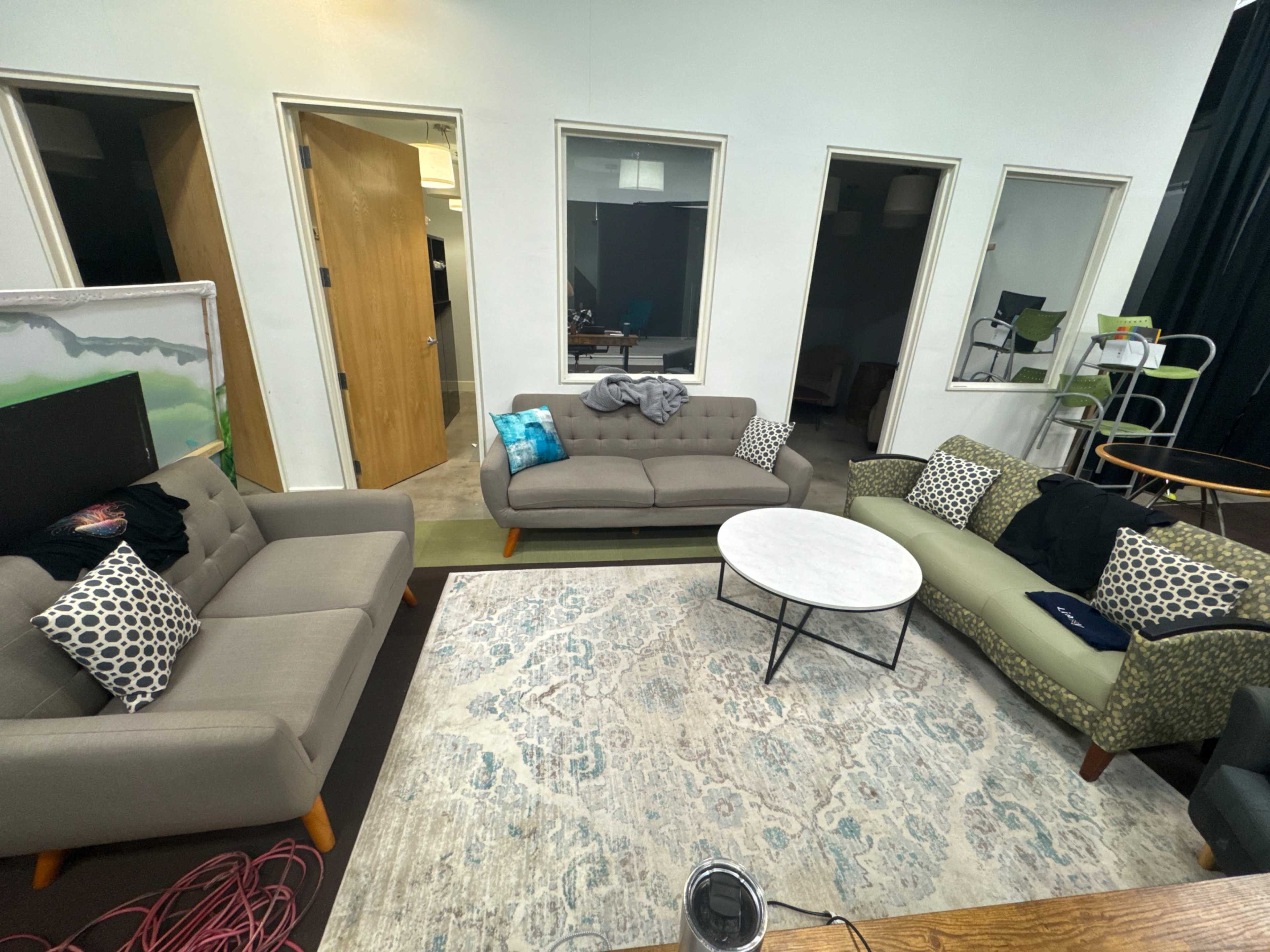 The image shows a casual lounge area with two sofas, a round marble coffee table, and several doorways leading to other rooms.