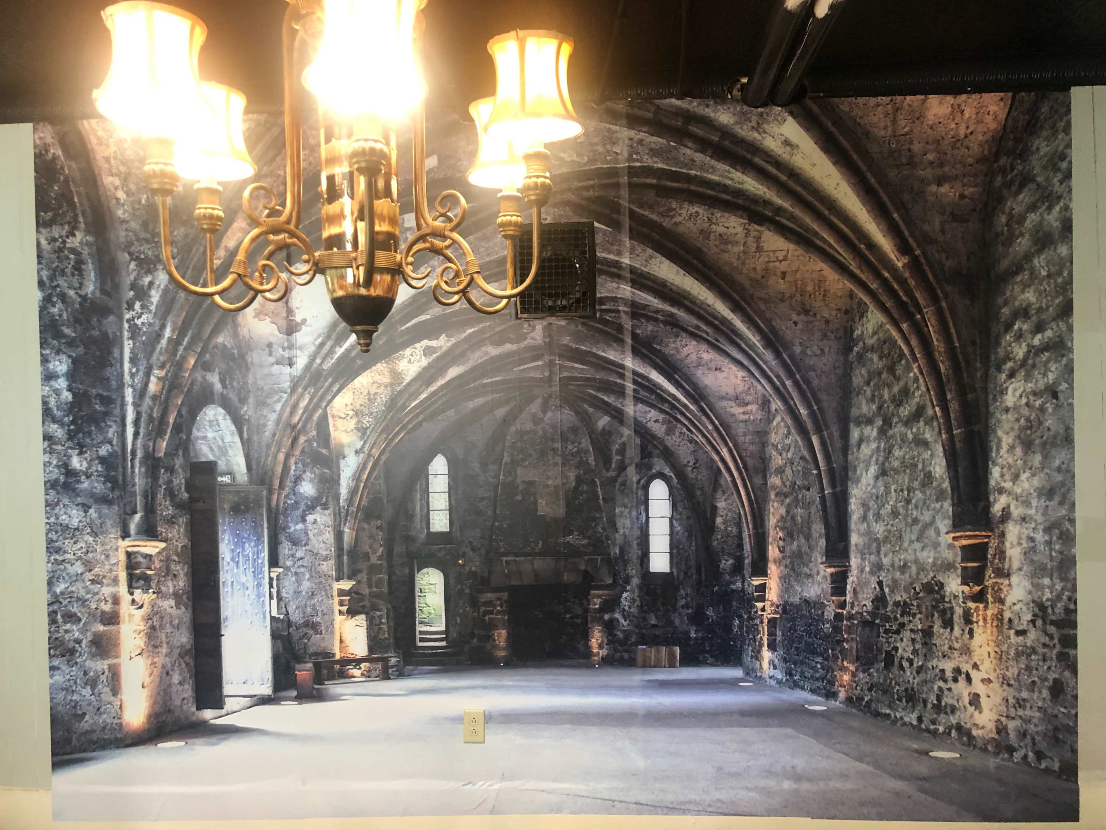 A large mural of an arched stone interior with a chandelier overhead, depicting the inside of an ancient building.