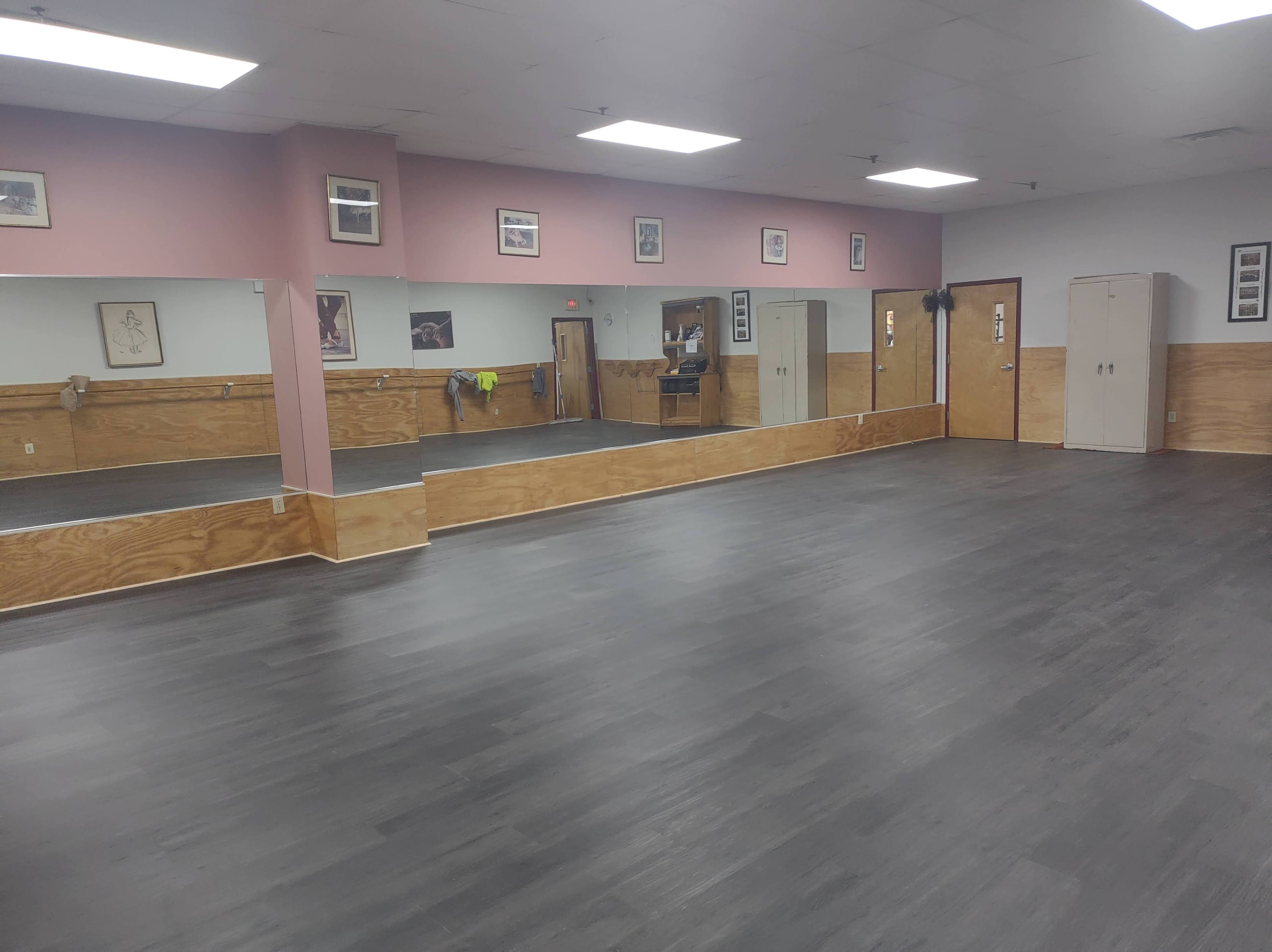 The image shows a spacious dance studio with mirrored walls and a wooden floor.