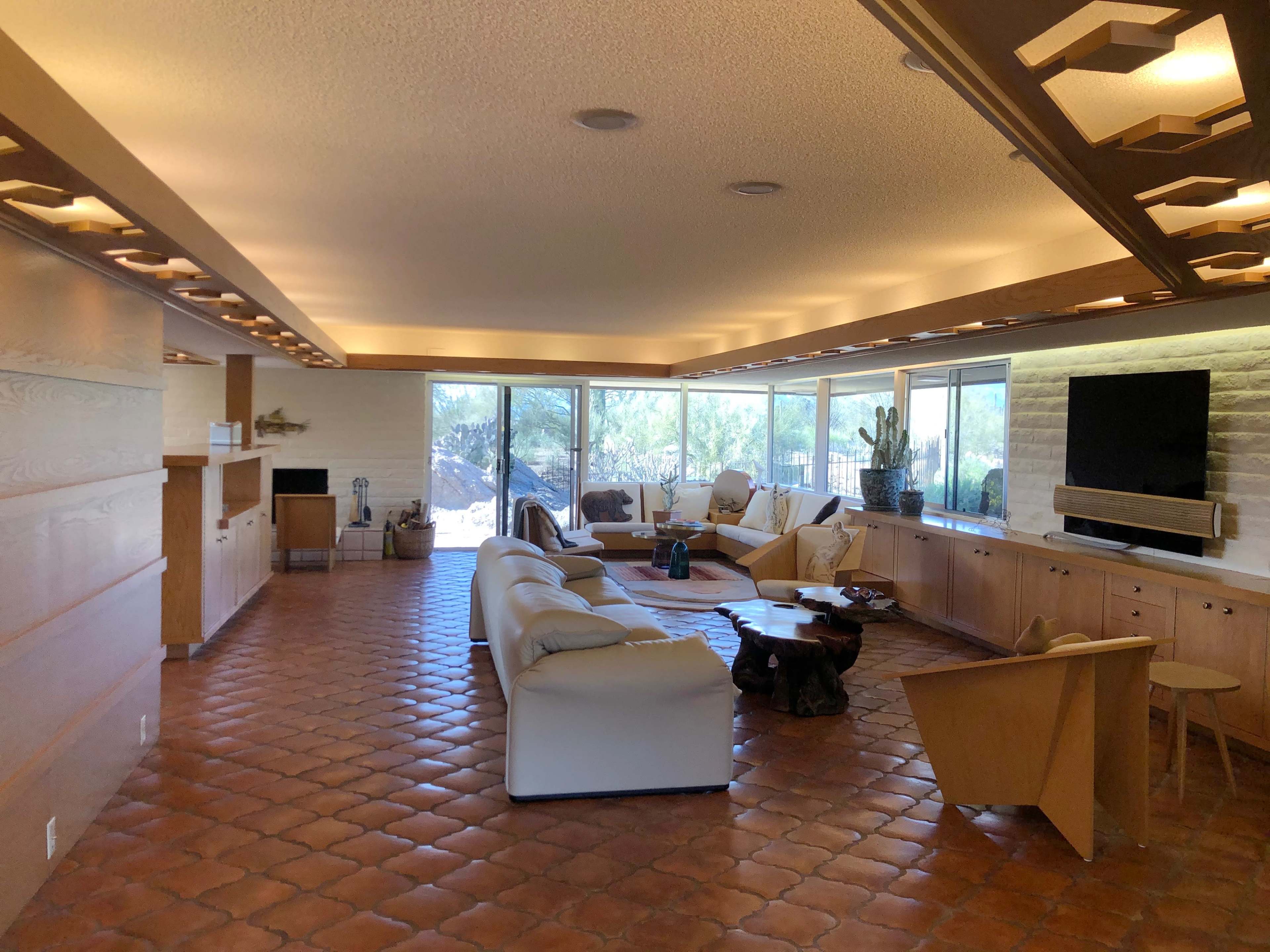 A spacious living room with large windows, featuring a mix of modern furniture and natural stone elements.