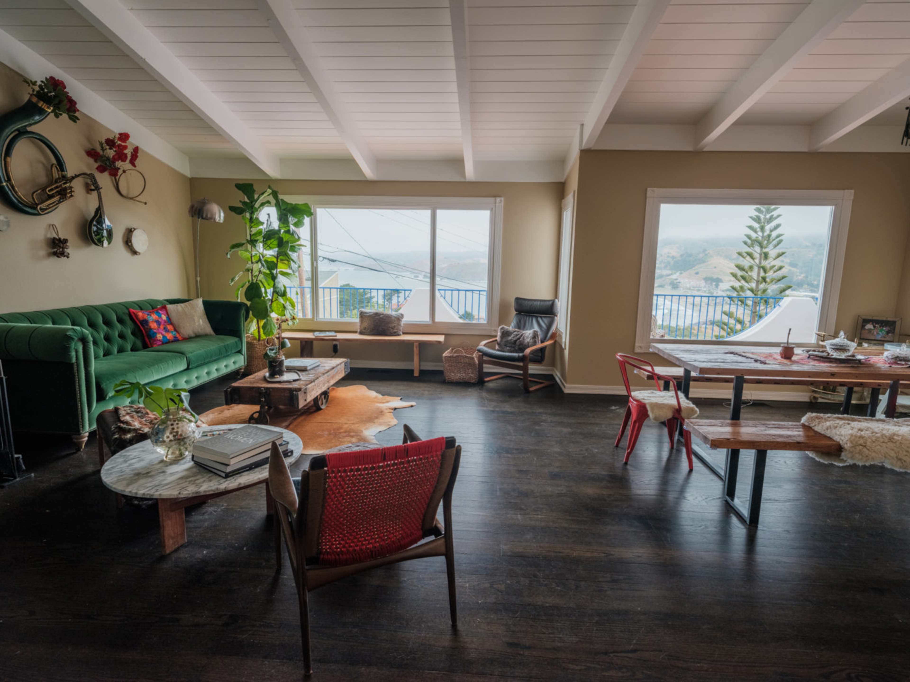 A spacious living room with a green sofa, wooden coffee table, and large windows overlooking a scenic view.