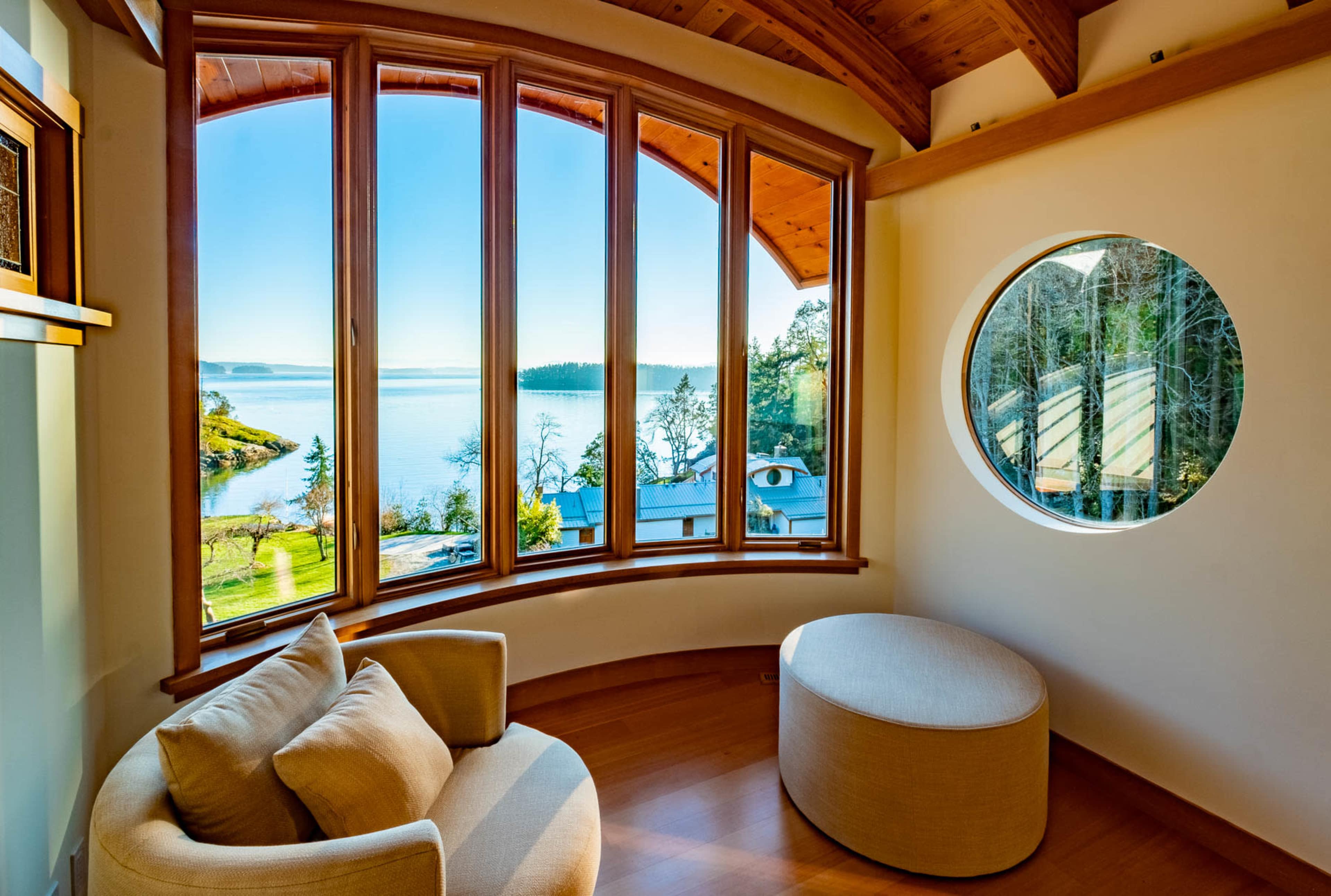 A cozy seating area features large windows overlooking a calm waterfront view.