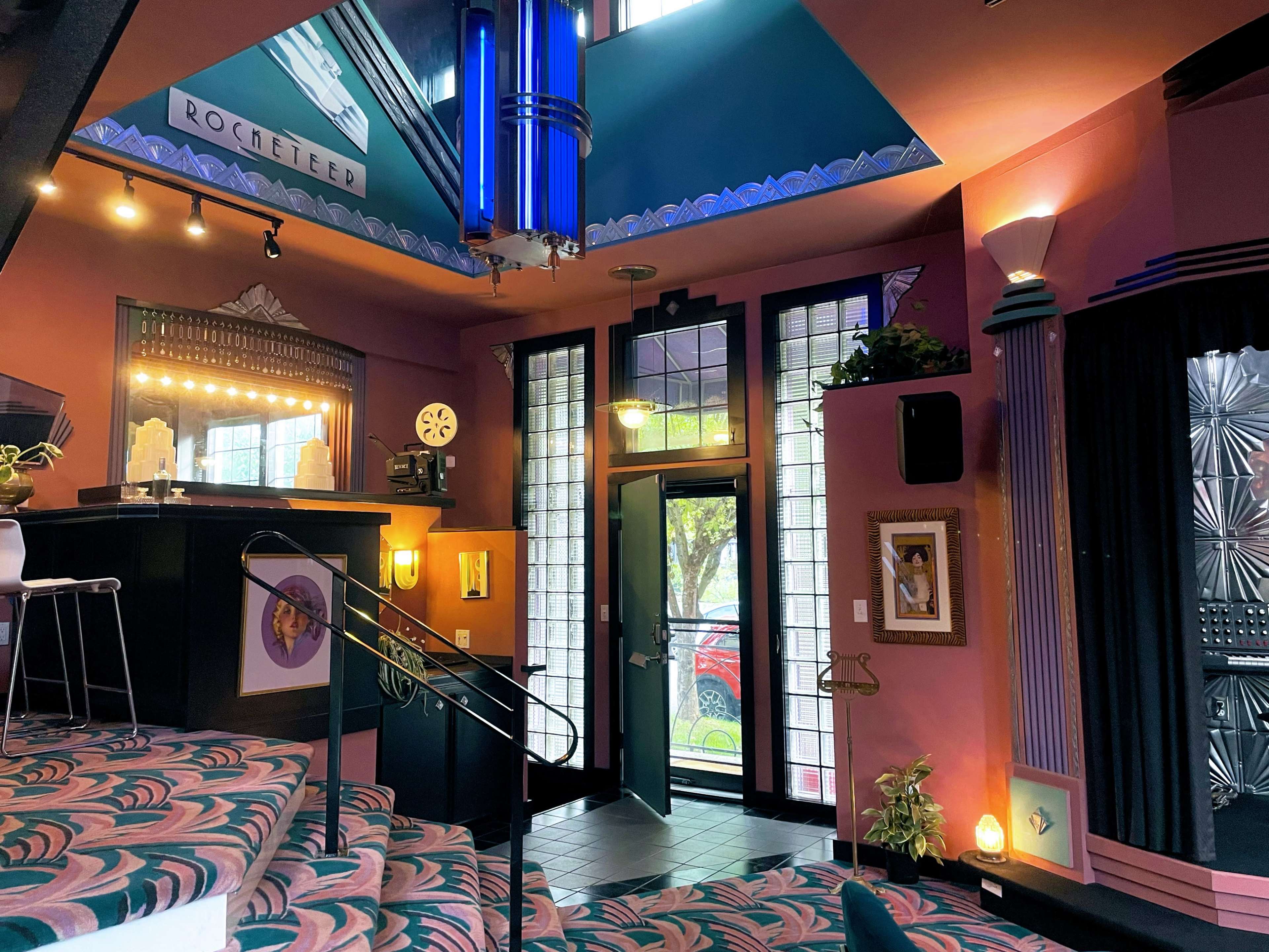 An interior space with colorful walls, a staircase leading to a raised area, and large windows that open to an outdoor view.