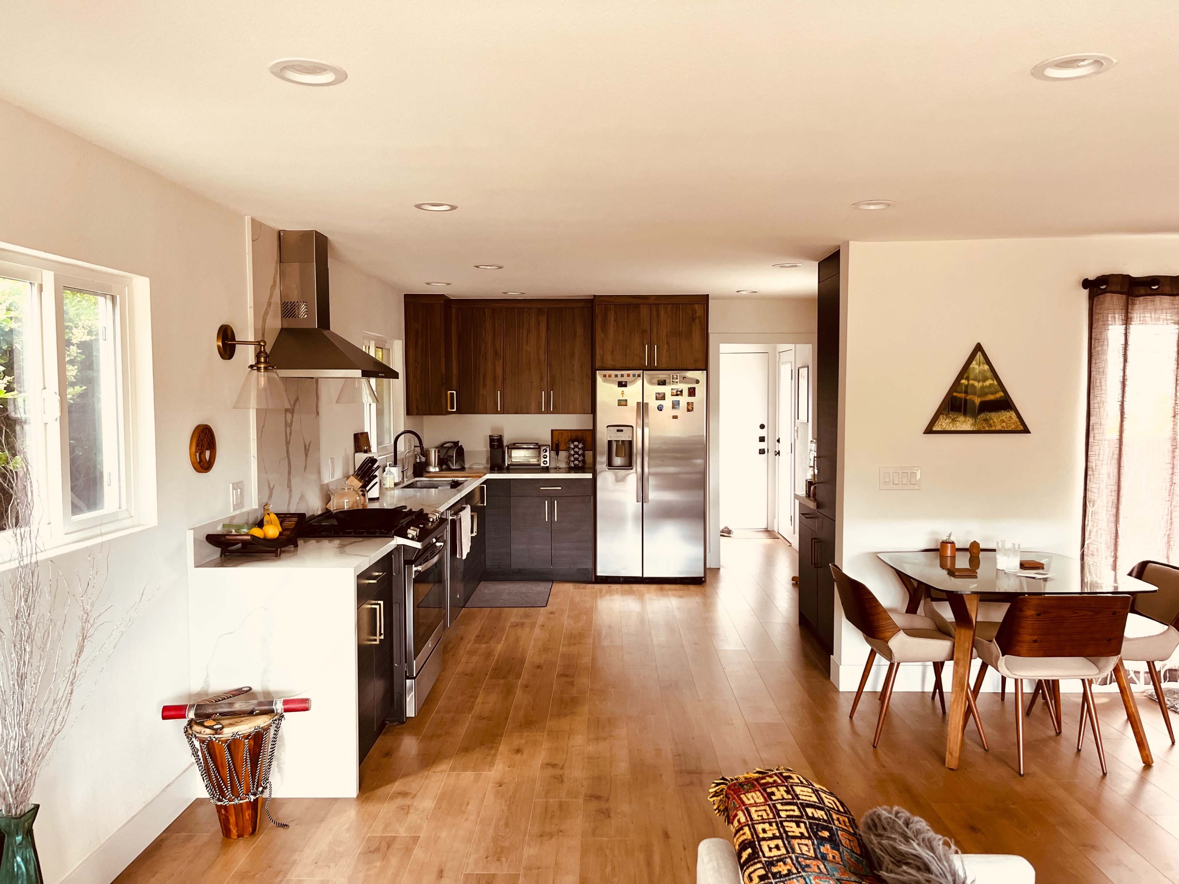 A modern kitchen and dining area with wooden flooring, stainless steel appliances, and a dining table set for four.